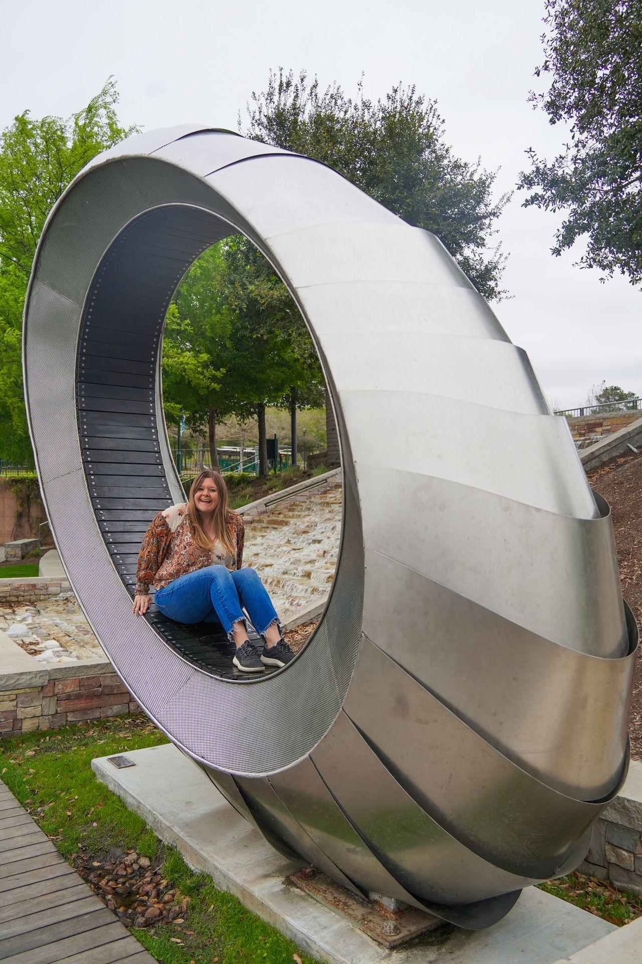 Lydia sitting in a large circular art bench in The Woodlands