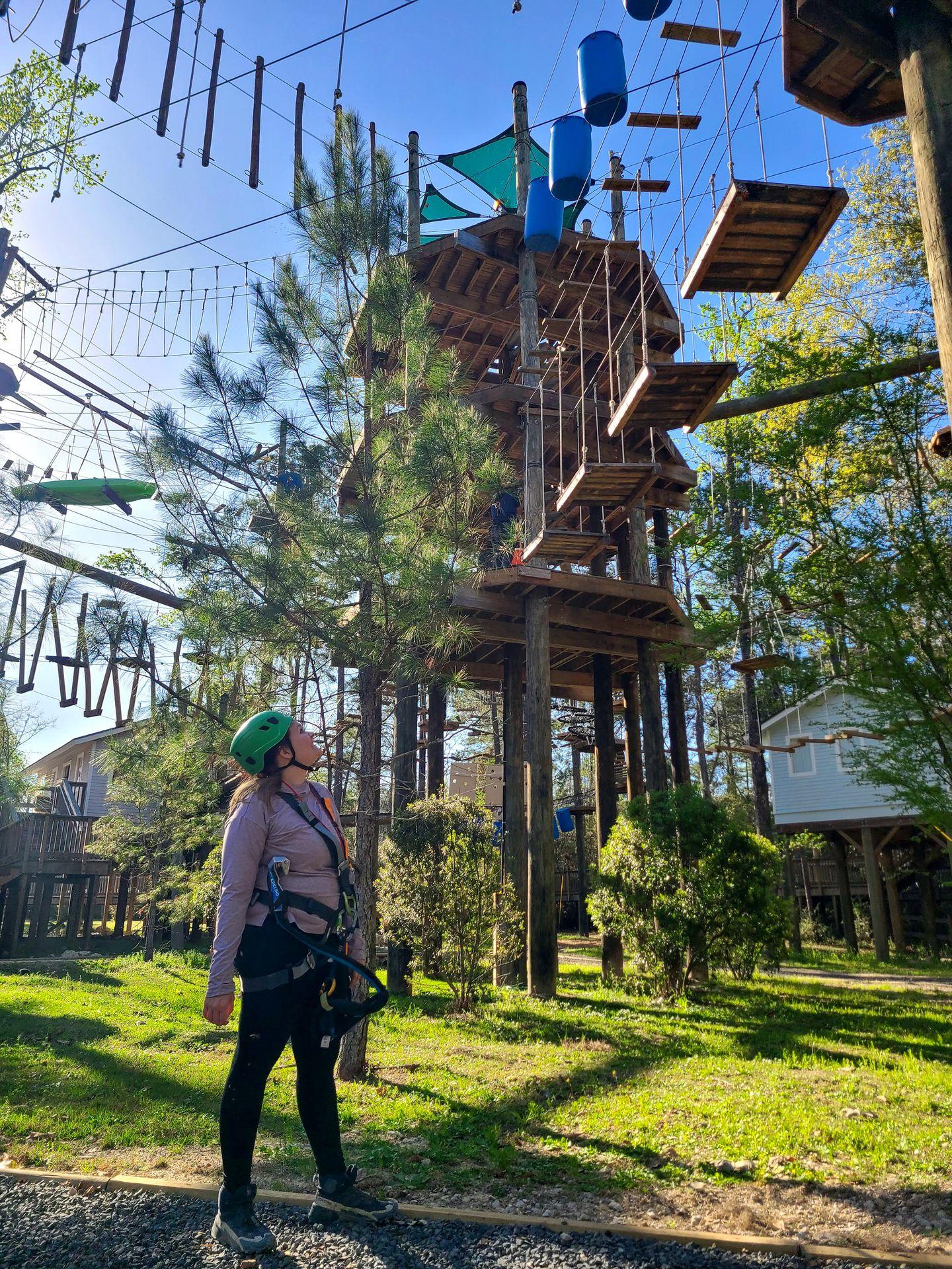 Lydia looking up at the Texas TreeVentures course wearing a harness and helmet
