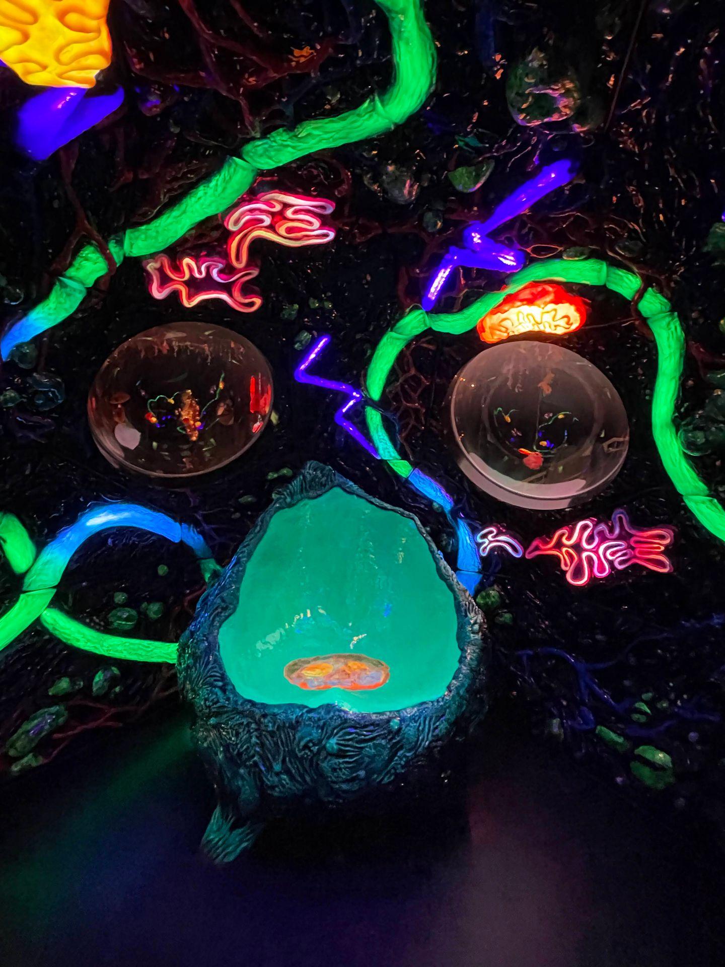 An abstract green chair is surrounded by neon lights at Meow Wolf.