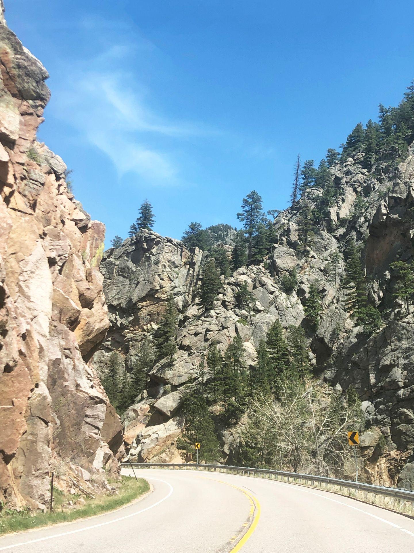 A road with huge, rock ledges on both sides.