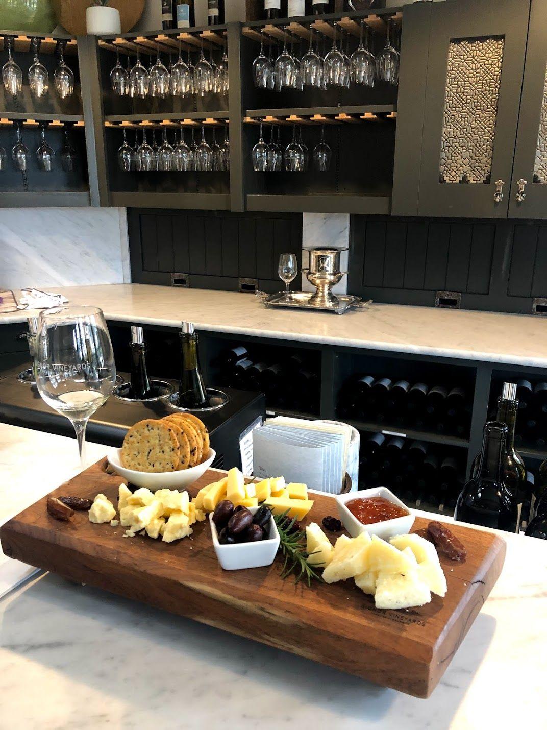 A cheese plate at the bar at Signor Vineyards. There are multiple cheeses, crackers, jam and berries.