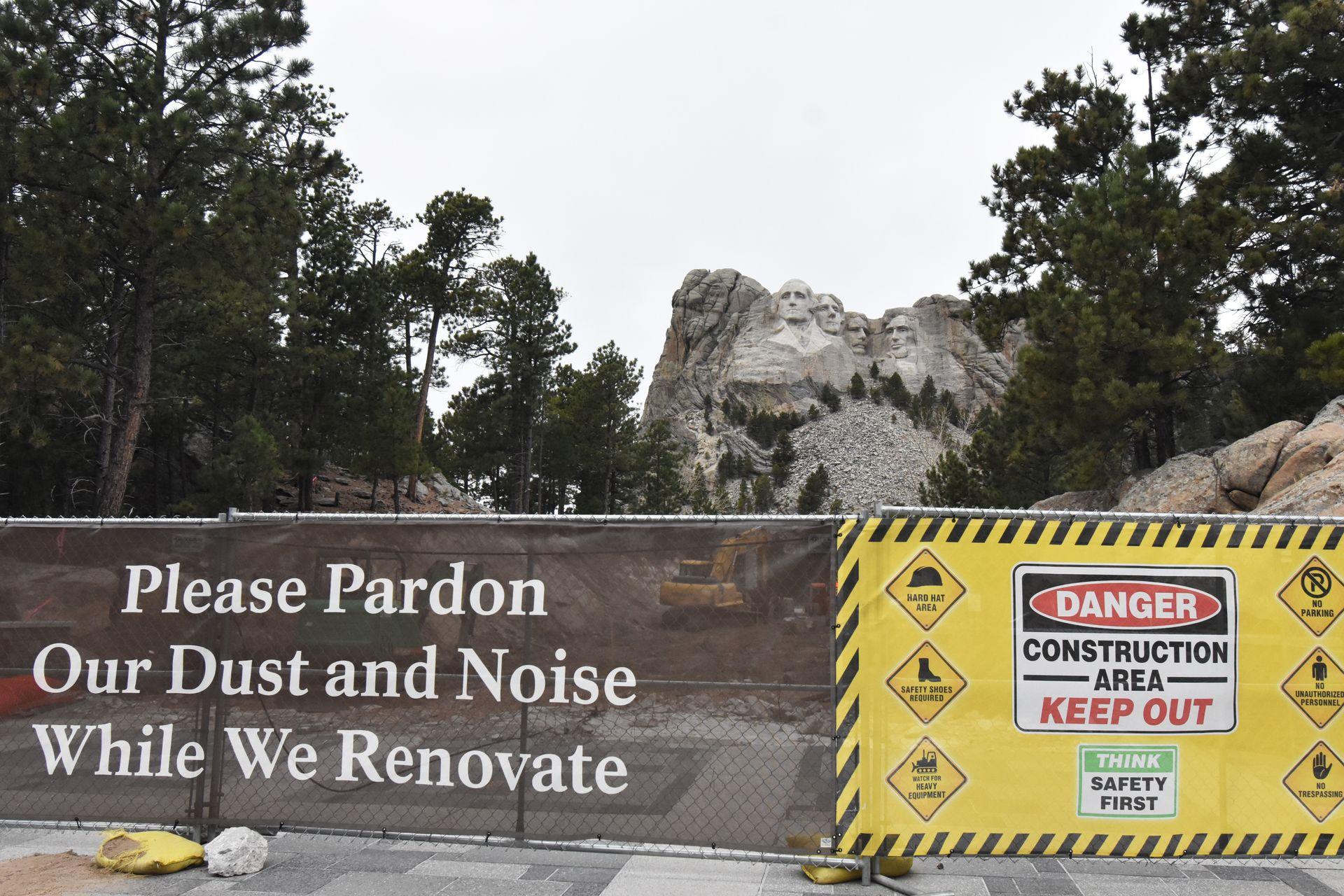 A construction fence with Mount Rushmore in the background.