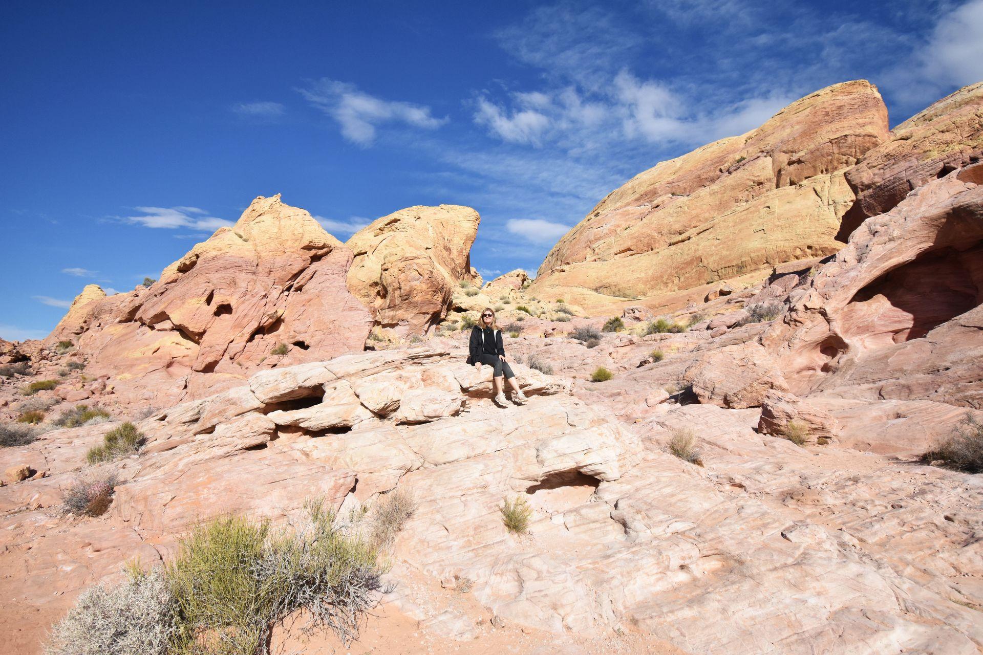 Lydia sitting on a vista of pink and orange rocks in Valley of Fire State Park.