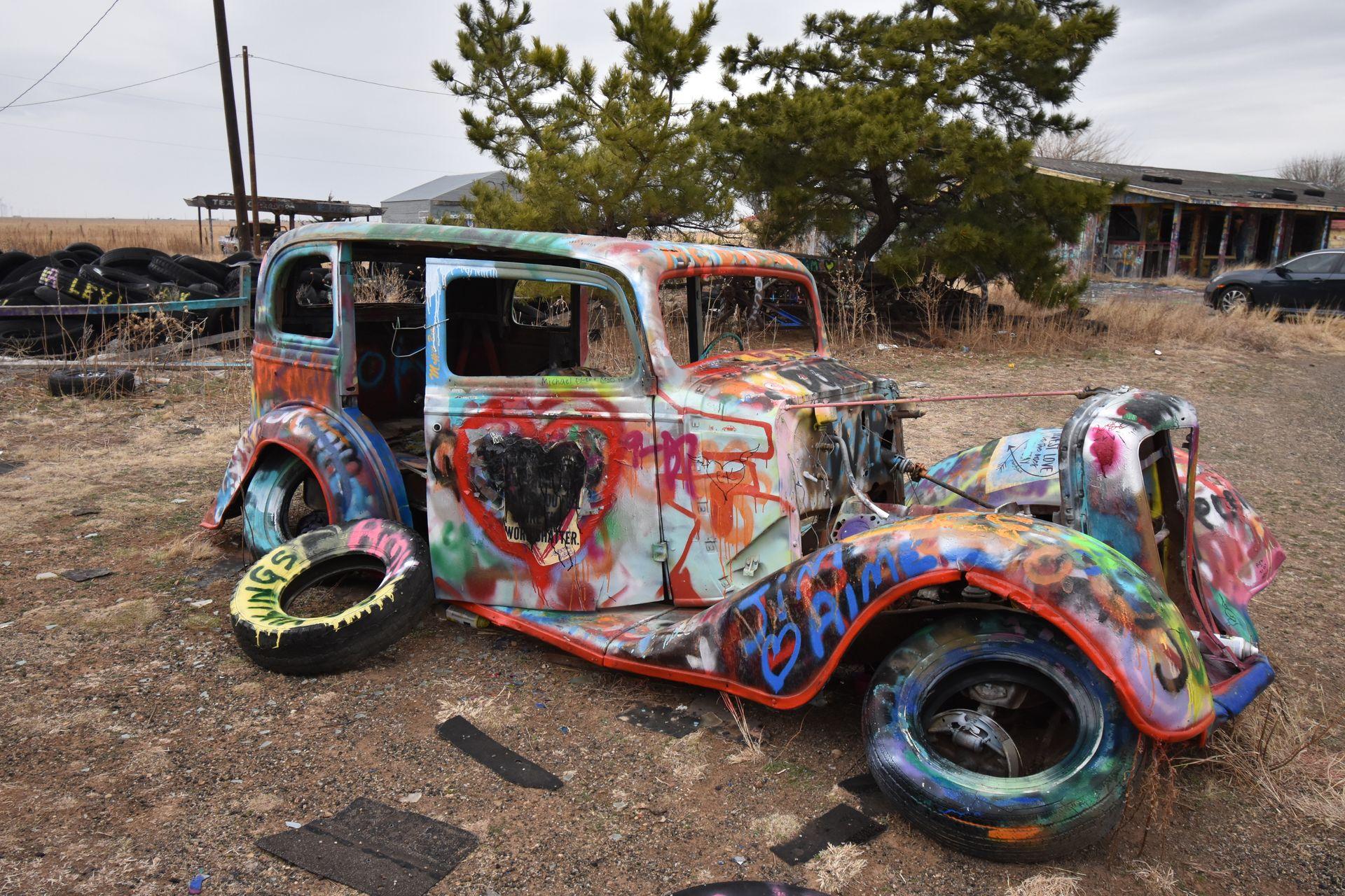 A vintage car covered in spray paint.