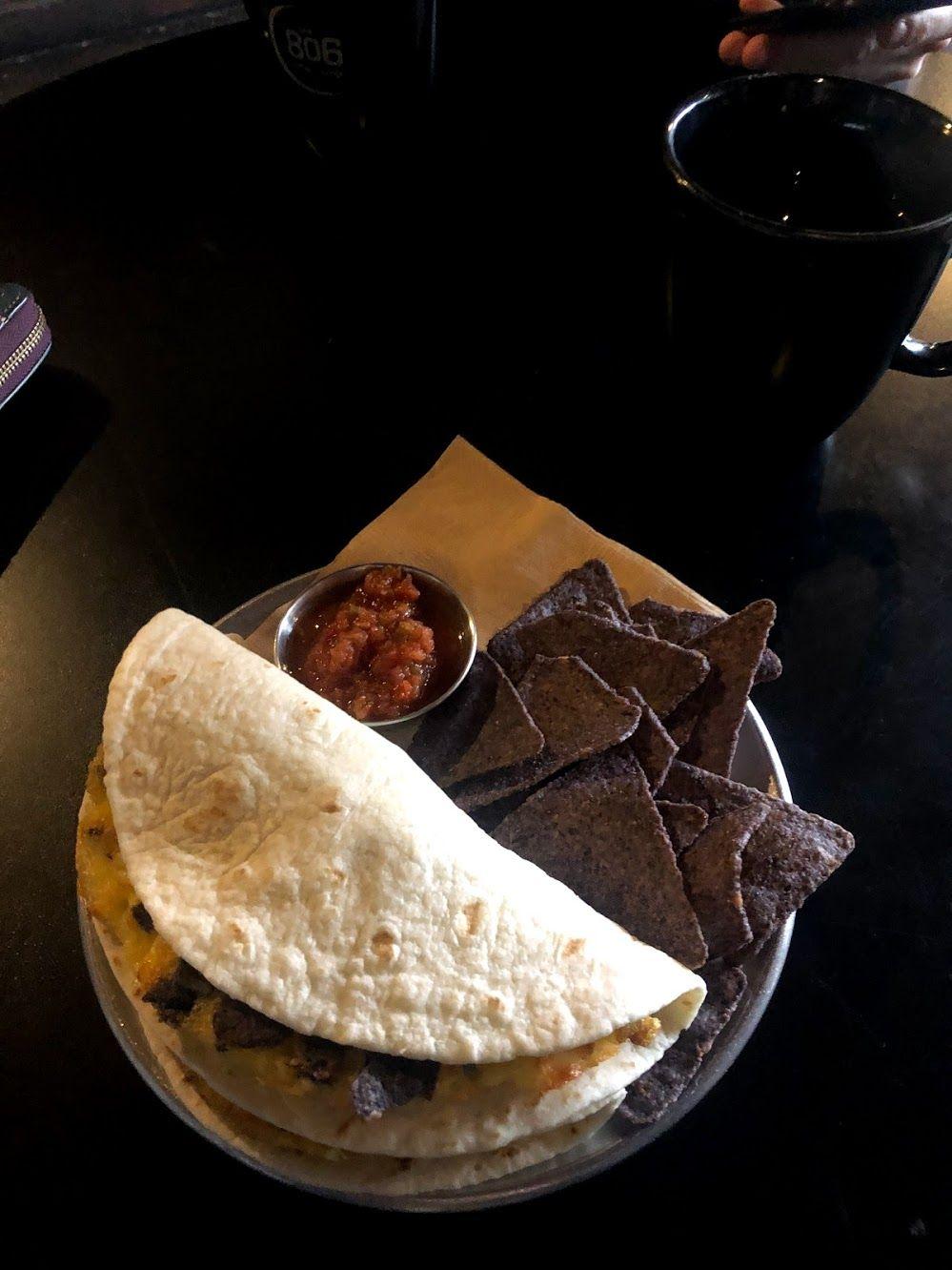 A taco sits next to chips and salsa on a plate on a table at the 806 Coffee + Lounge.