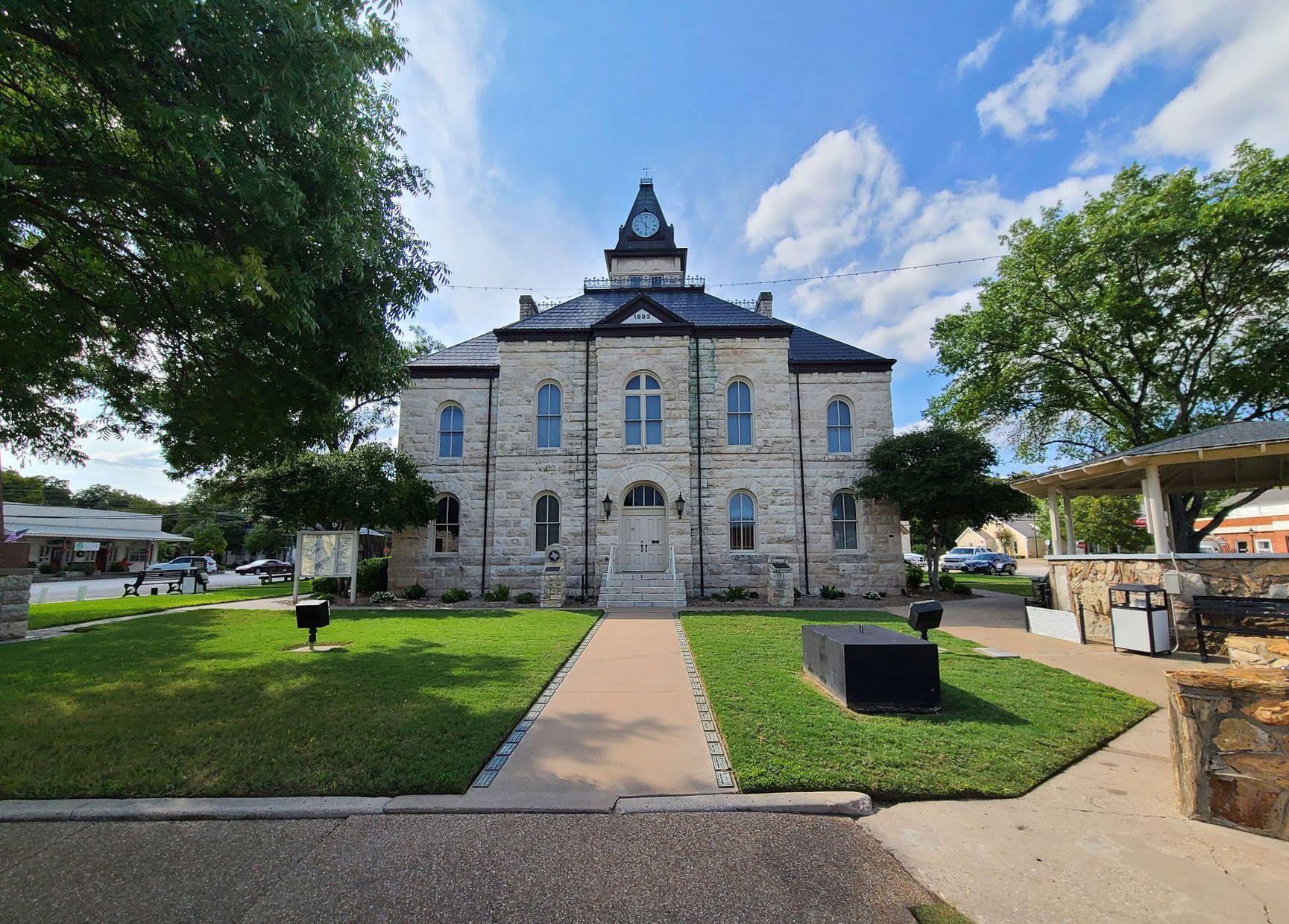 A view of the Glen Rose Courthouse. The buliding is white with a navy blue roof.