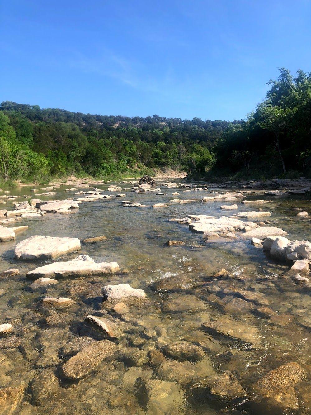 A view of the Paluxy River with several rocks in the water.