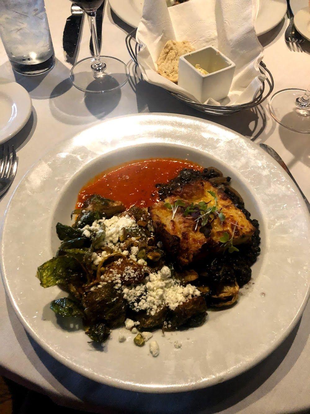 A plate with cauliflower, brussel sprouts and a red sauce.