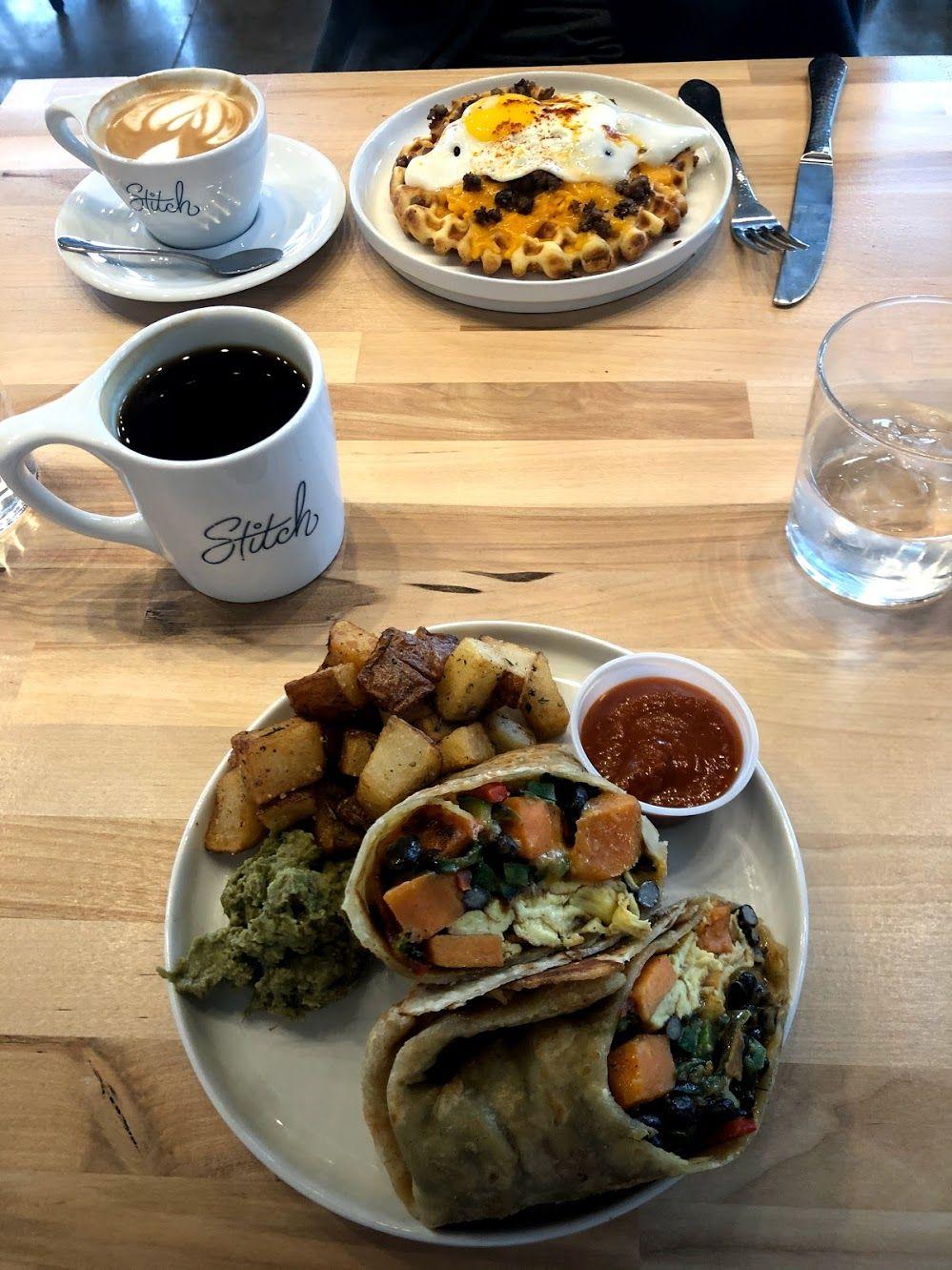 A burrito with sweet potatoes, eggs and greens. There are potatoes next to it on the plate.