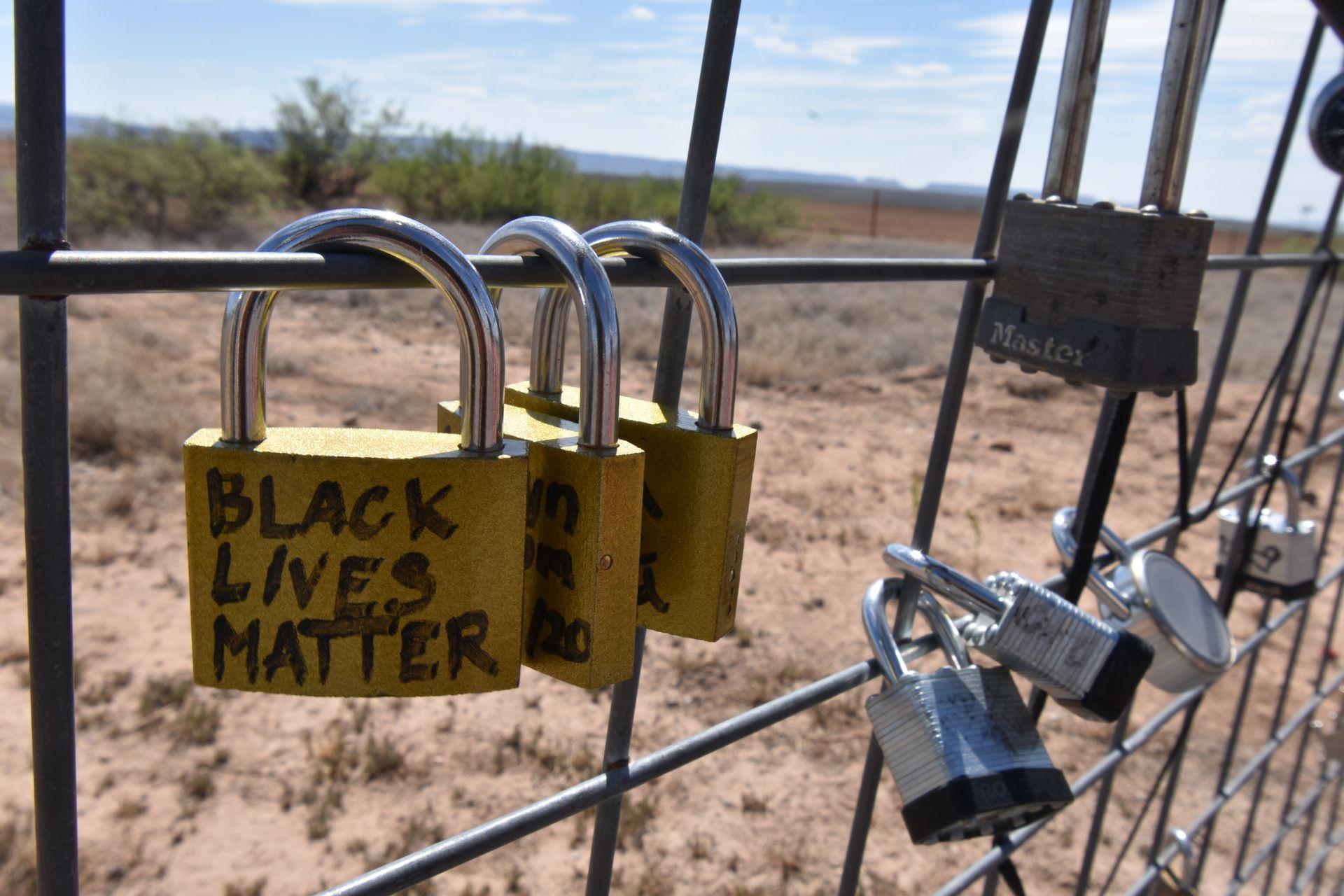 A close up of locks hanging on the fence behind Prada Marfa. The closest one reads 'Black Lives Matter'