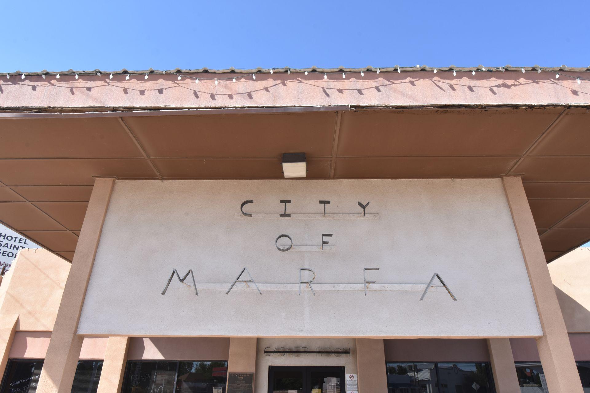 A pink, art deco style sign that reads 'City of Marfa'