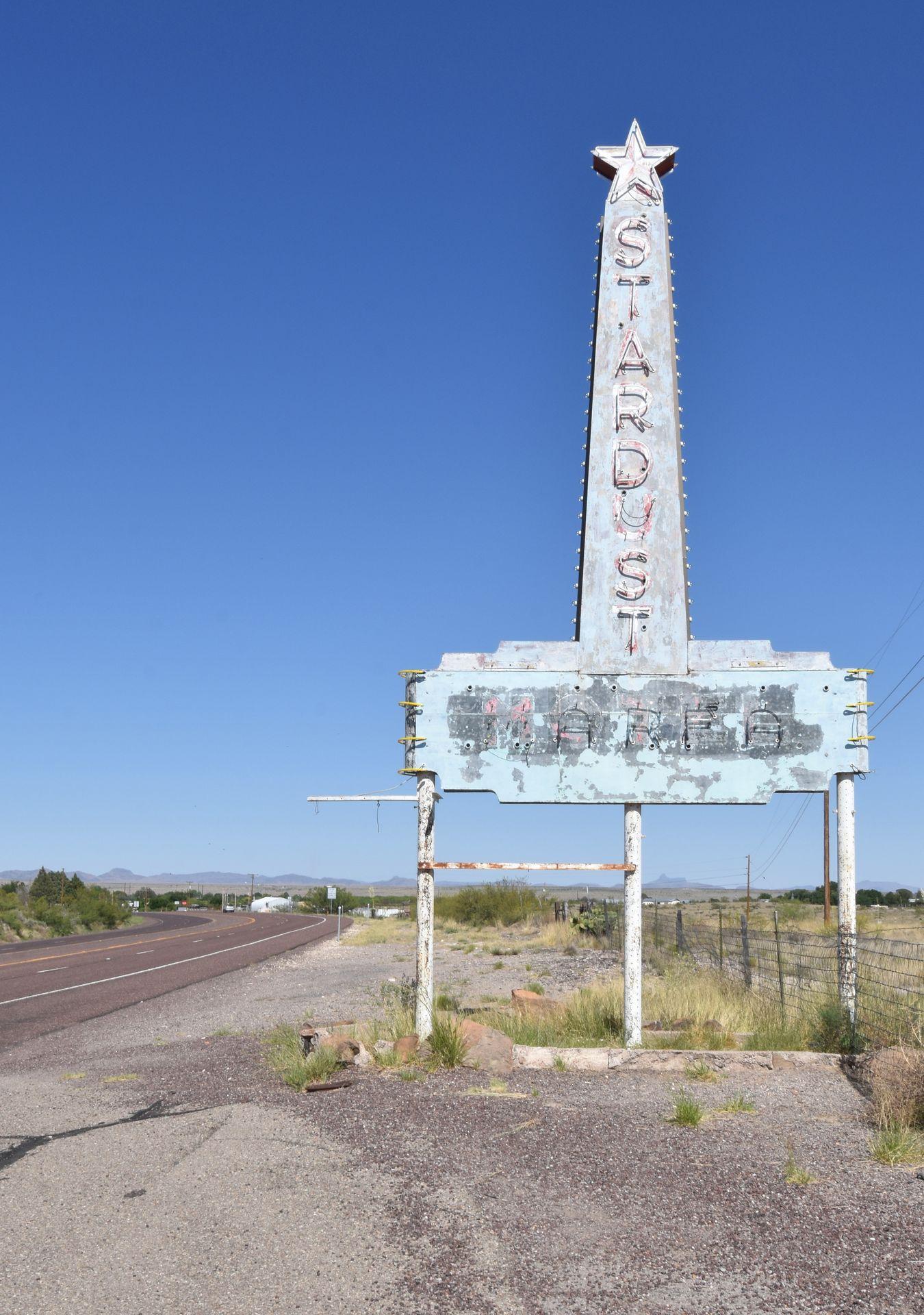 A large, faded sign on the side of the road that faintly reads 'Stardust'