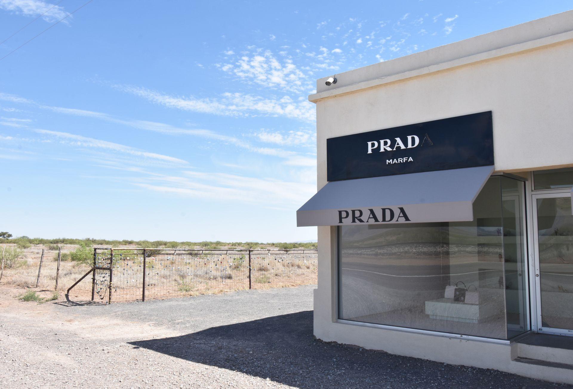 A Prada Store next to a fence with locks, with the desert in the background.
