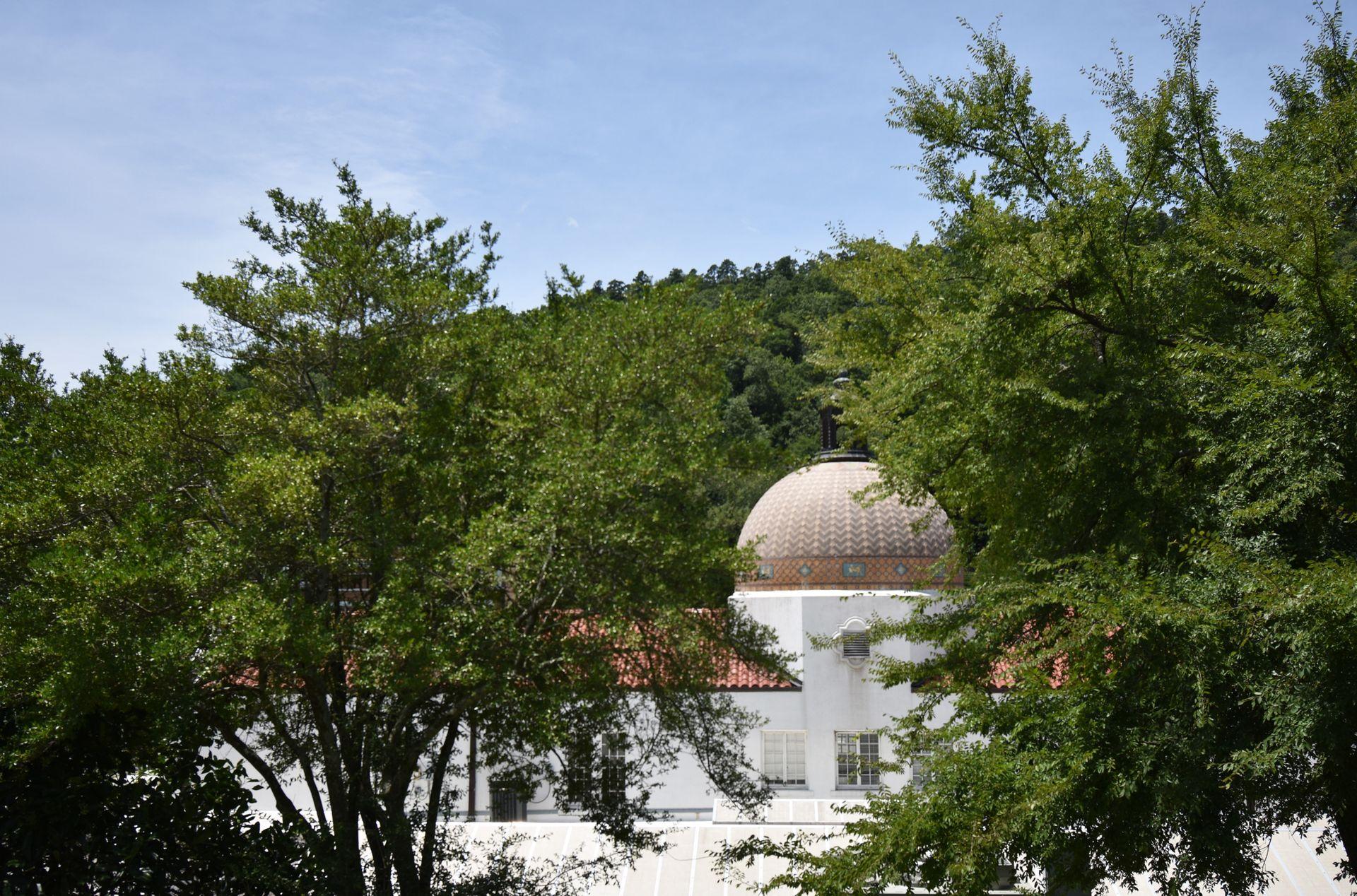 The back of the Quapaw Bathhouse. The building with white with a brown dome and the dome has a geometric pattern.