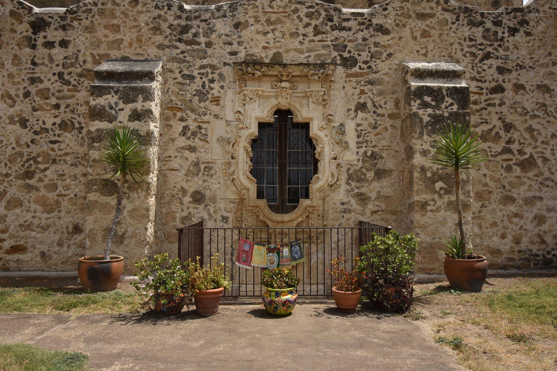 A window at Mission San Jose with some plants sitting outside.