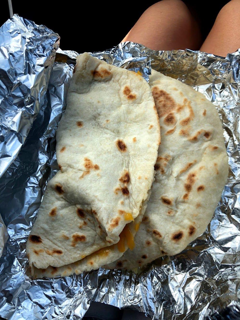 A close up of two tacos sitting on aluminum foil.