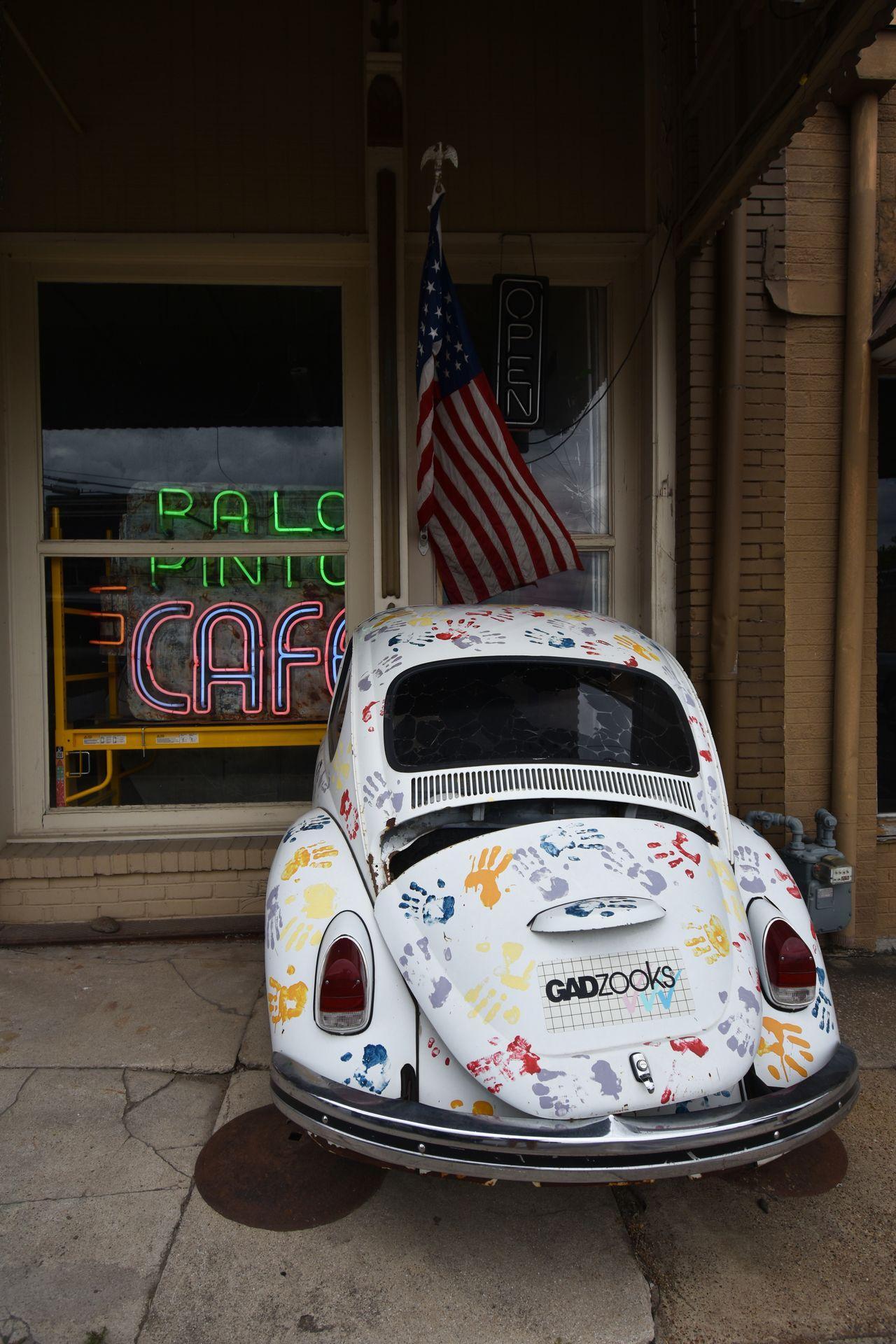 A white Volkswagen beetle with colorful paintprints on it.