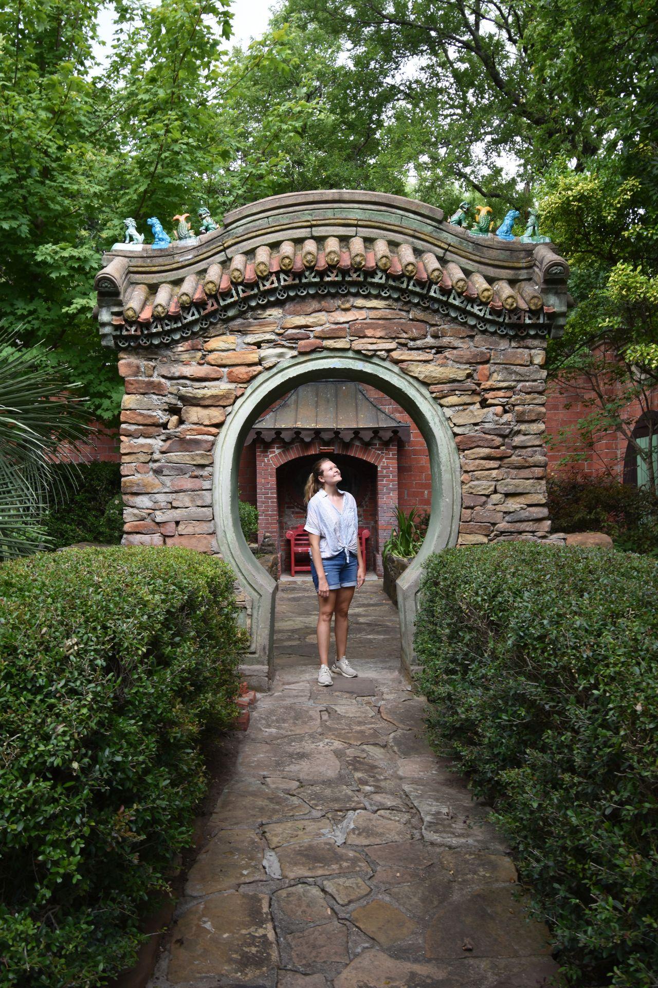 Lydia standing under a stone archway at Chandor Gardens