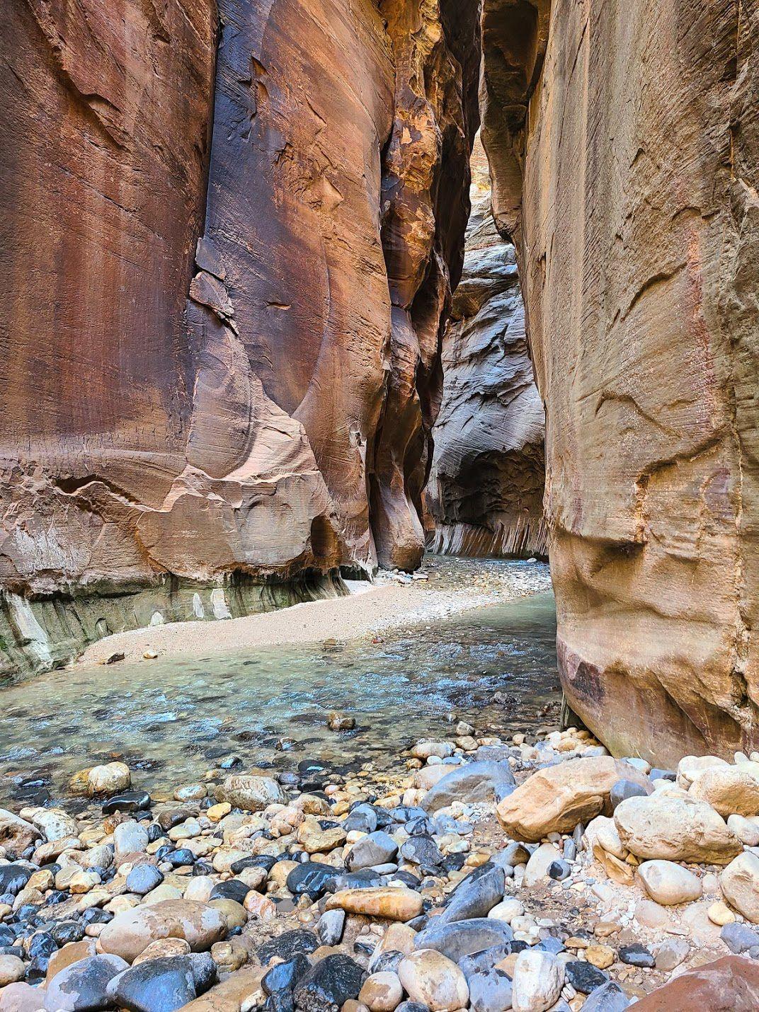 A view of the river flowing between tall canyon walls on The Narrows trail.