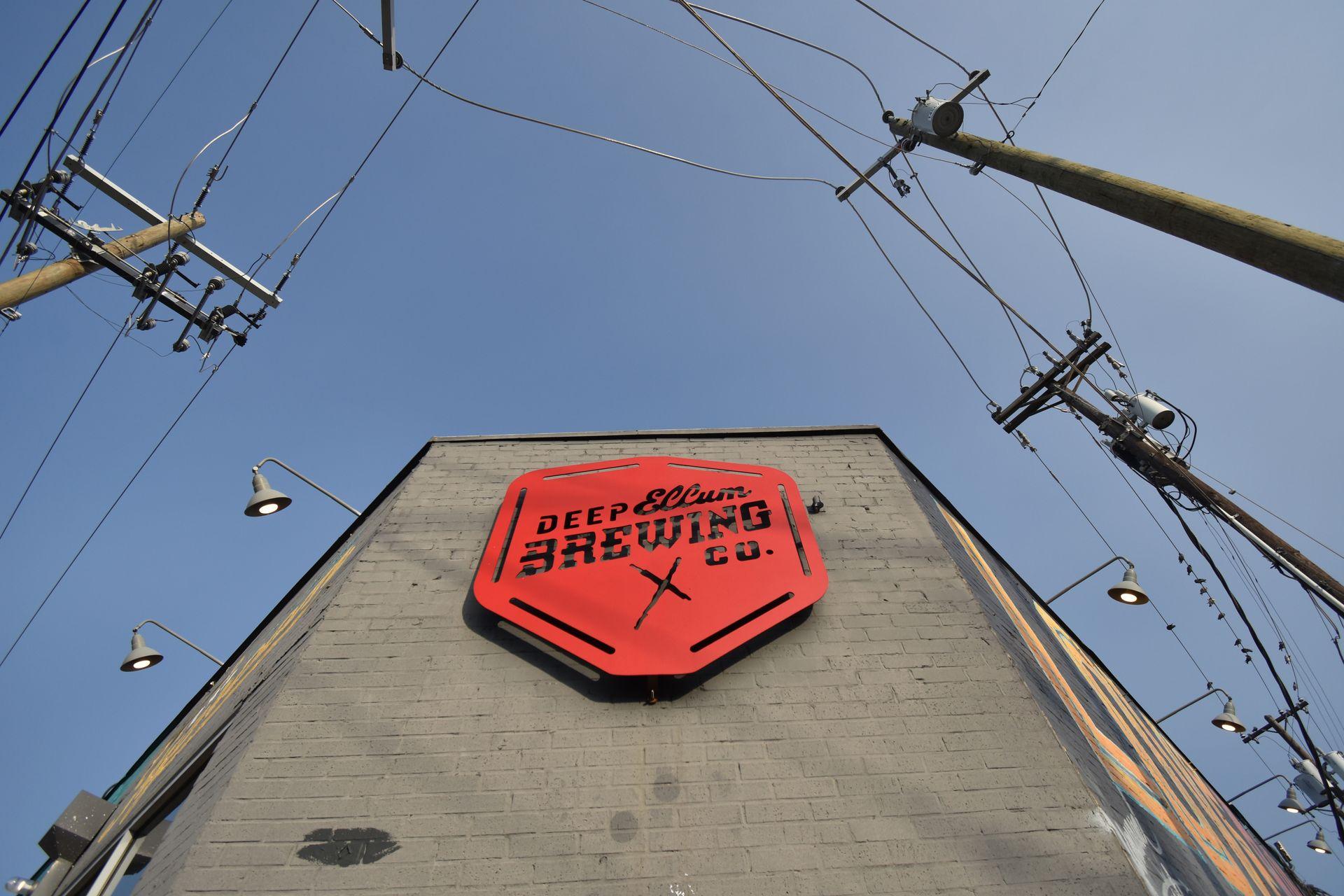 Looking up at the exterior of Deep Ellum Brewery. Their logo is in red.