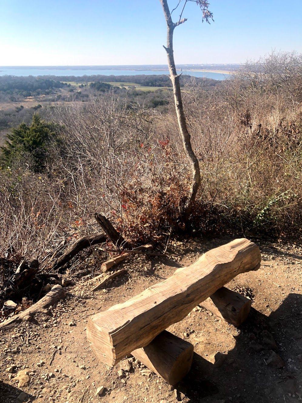 A bench next to an overlook with a lake in the distance.