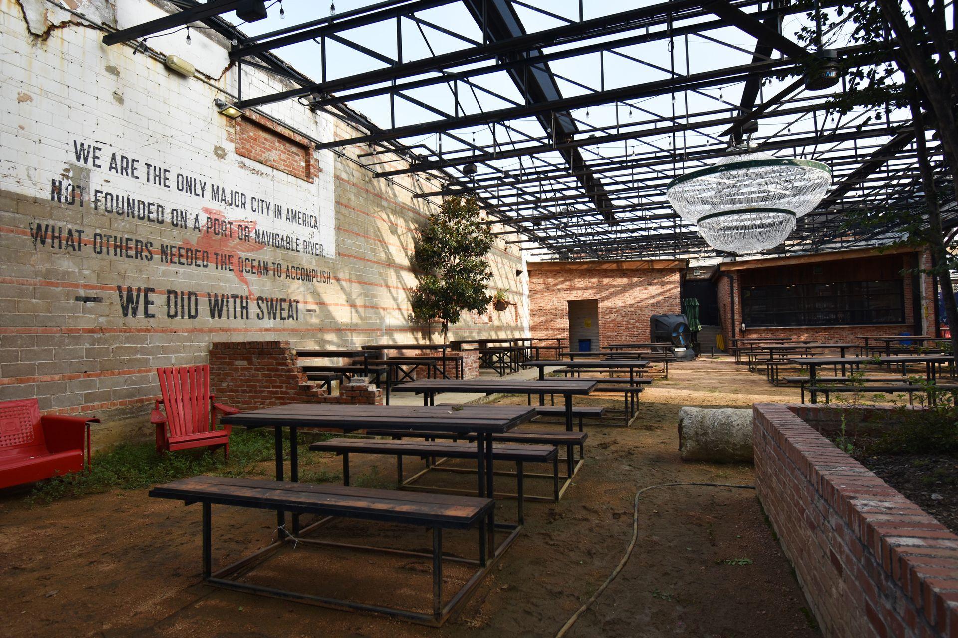 The outdoor courtyard space with several tables at Dot's. There is a quote on the wall about Dallas