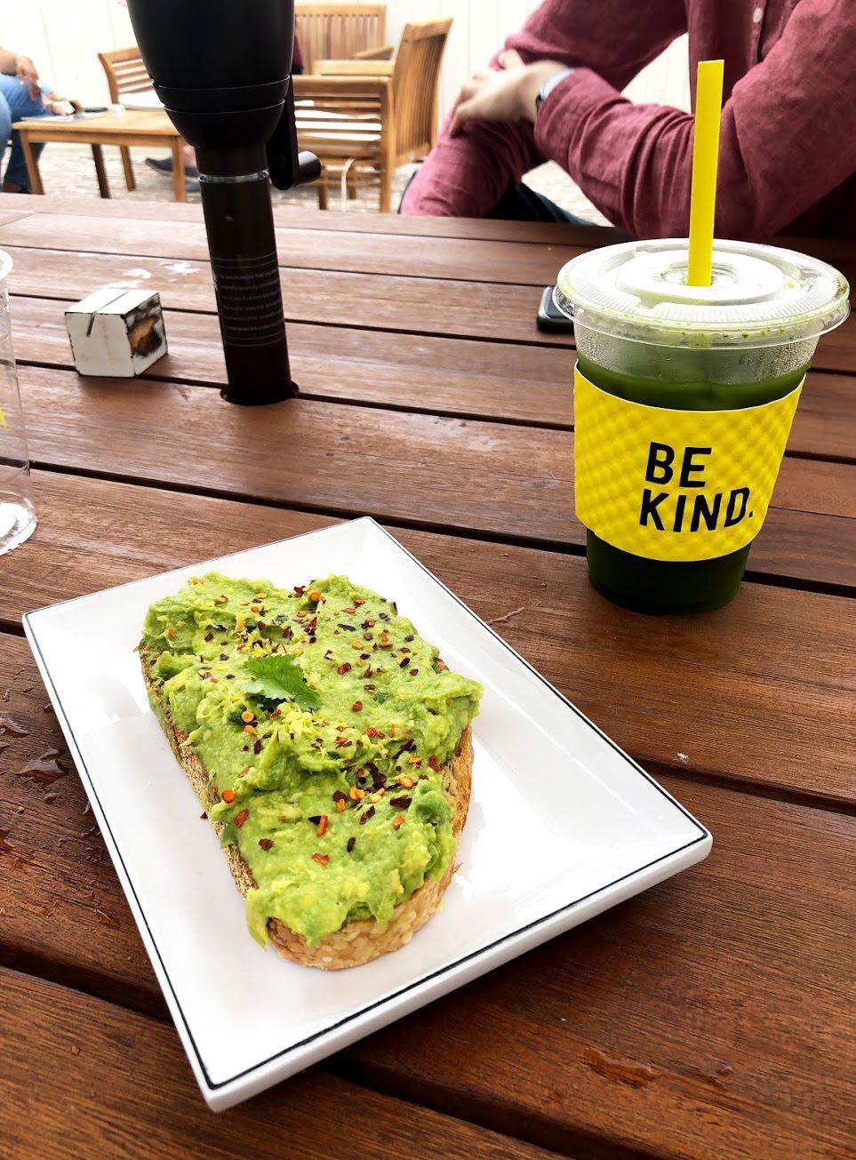 Avocado toast on a white plate with a cold, green drink from La La Land Kind Cafe.