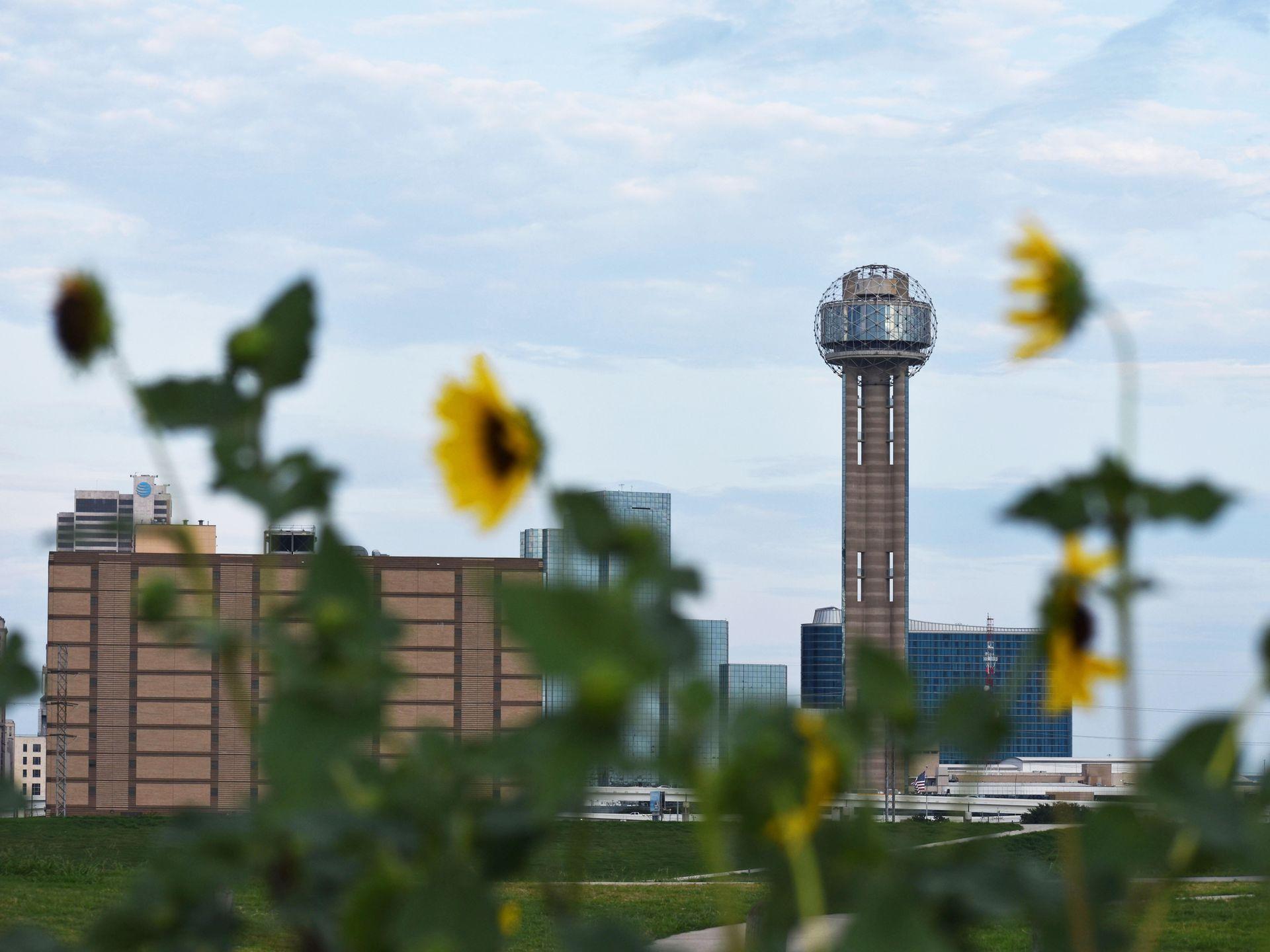 A view of Reunion Tower with some blurred sunflowers in the foreground.