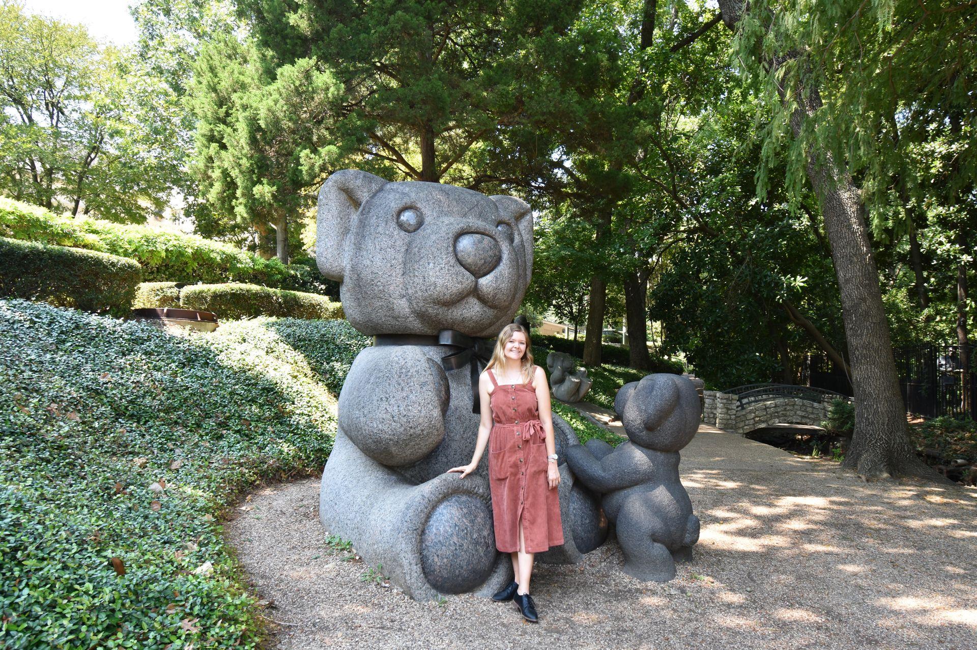 Lydia standing in front of a giant teddy bear statue.