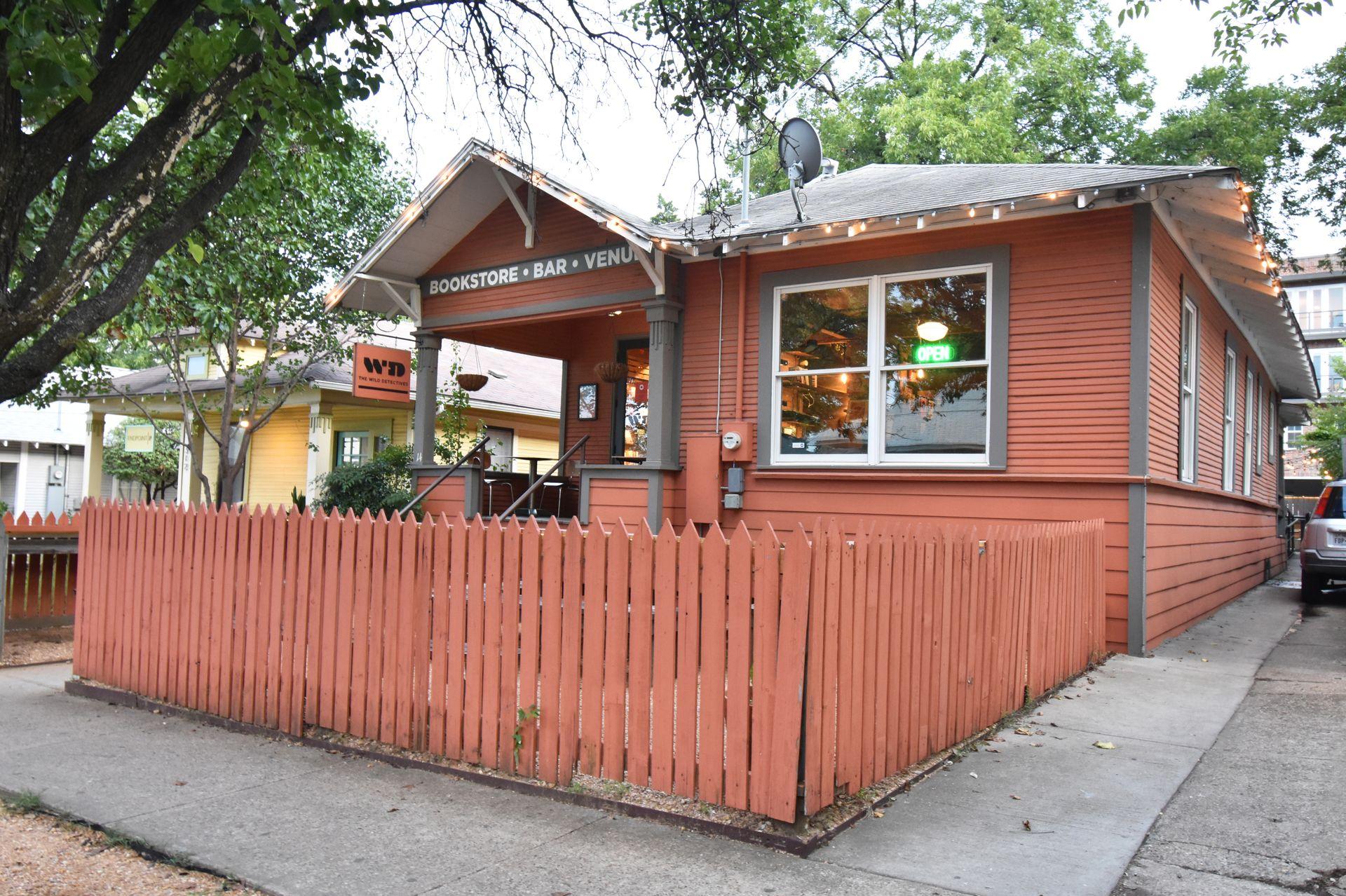 The exterior of Wild Detectives. The building is orange with a fence around the front patio space.