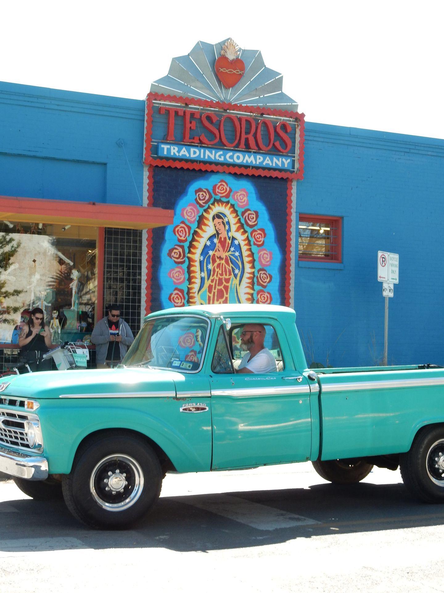 A blue pick up truck in front of Tesoros Trading Company.