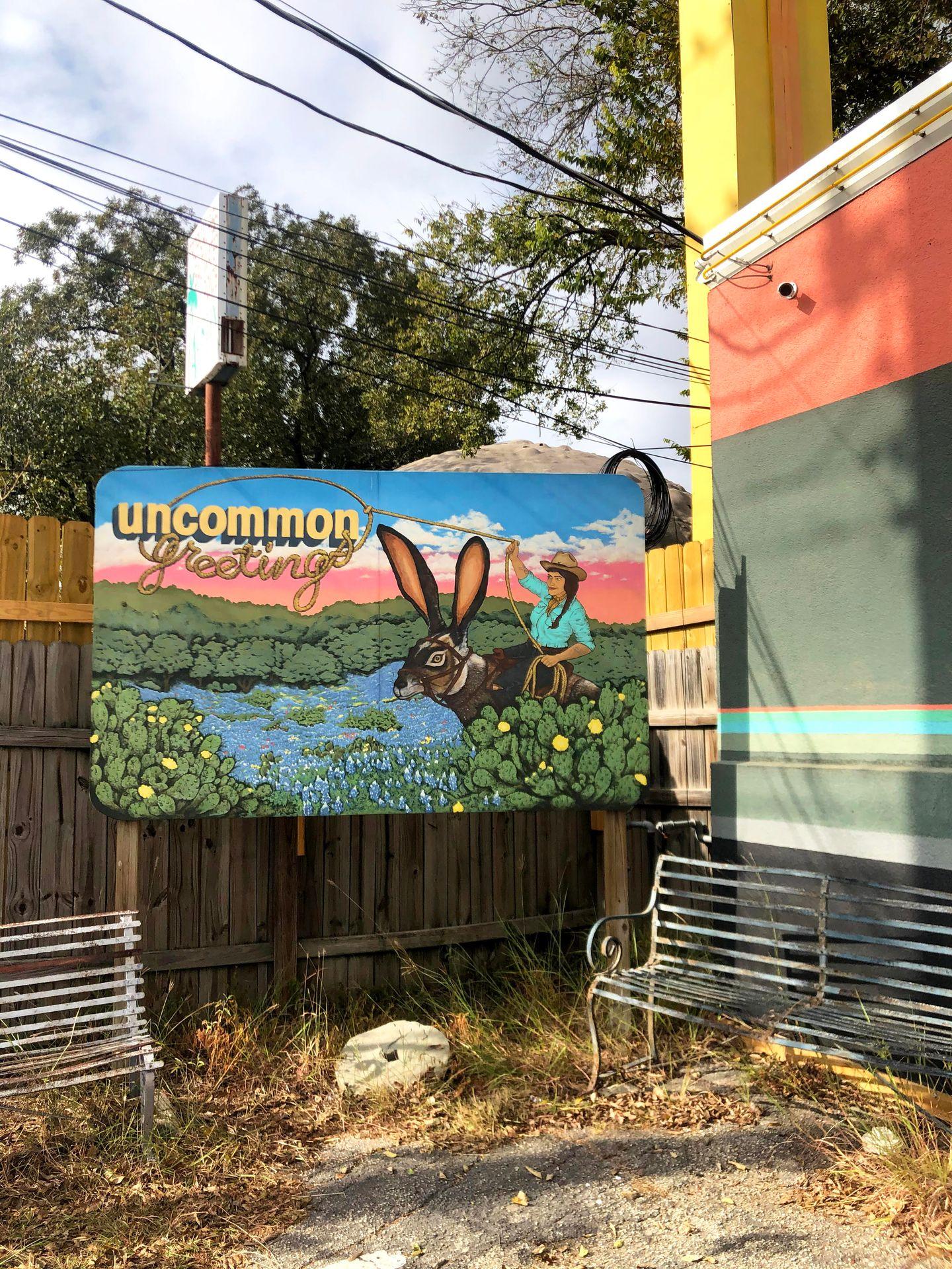 A painted sign outside of Uncomming Objects of someone riding a bunny.