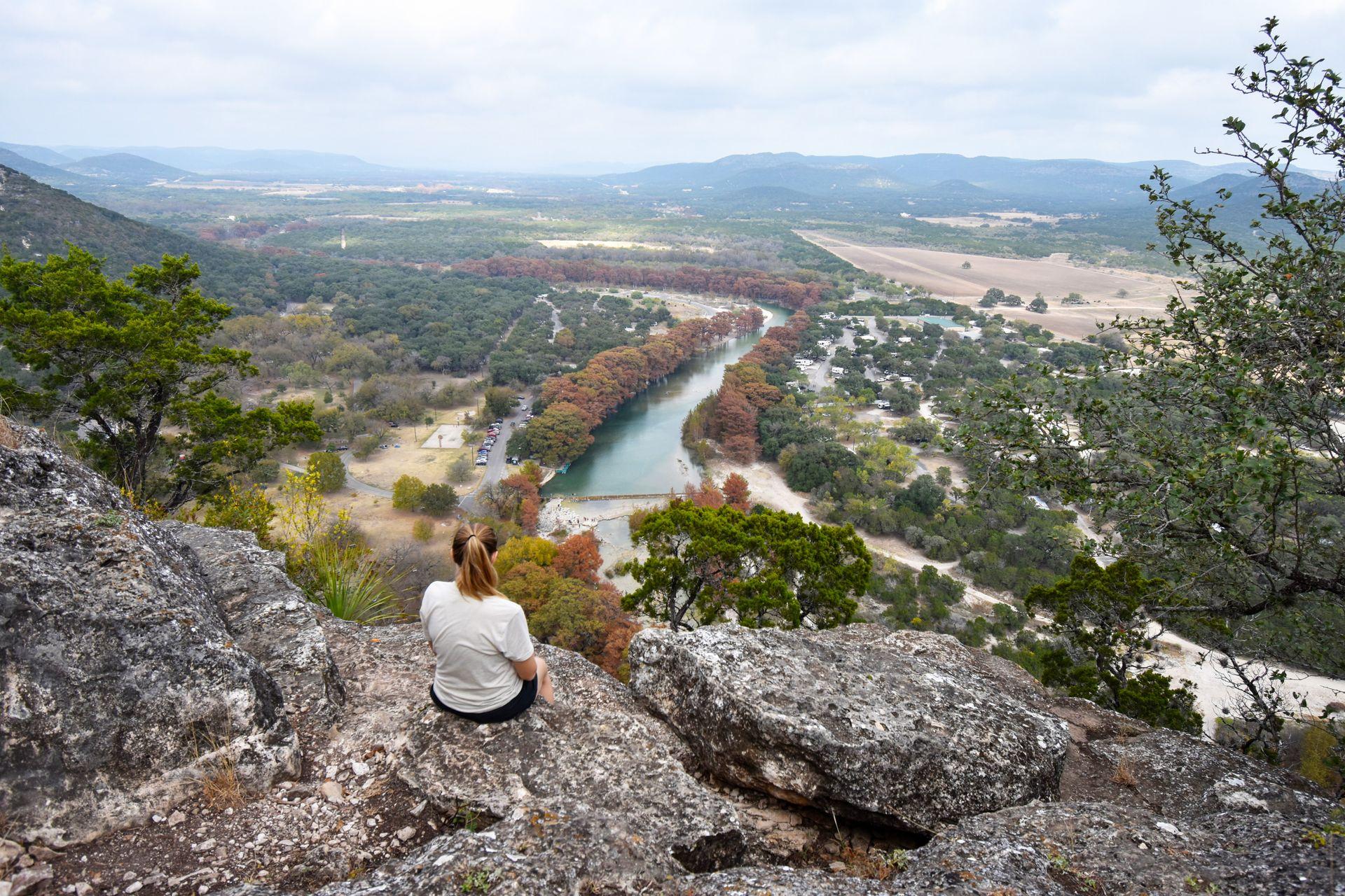 Lydia sitting on the edge of a rock looking out at the Frio River on the Mt Baldy trail