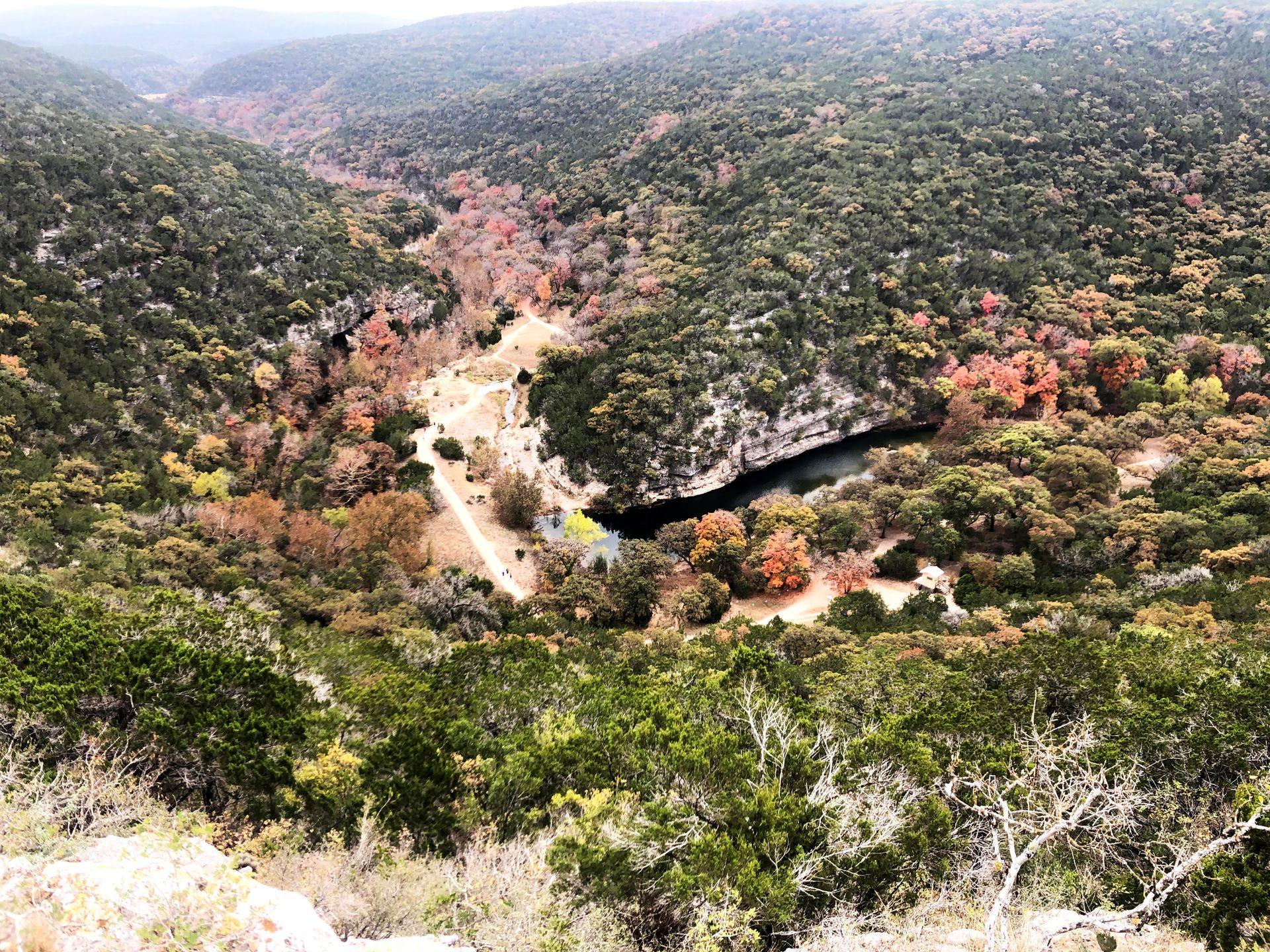 An overlook view in Lost Maples with a river and hills covered in trees.