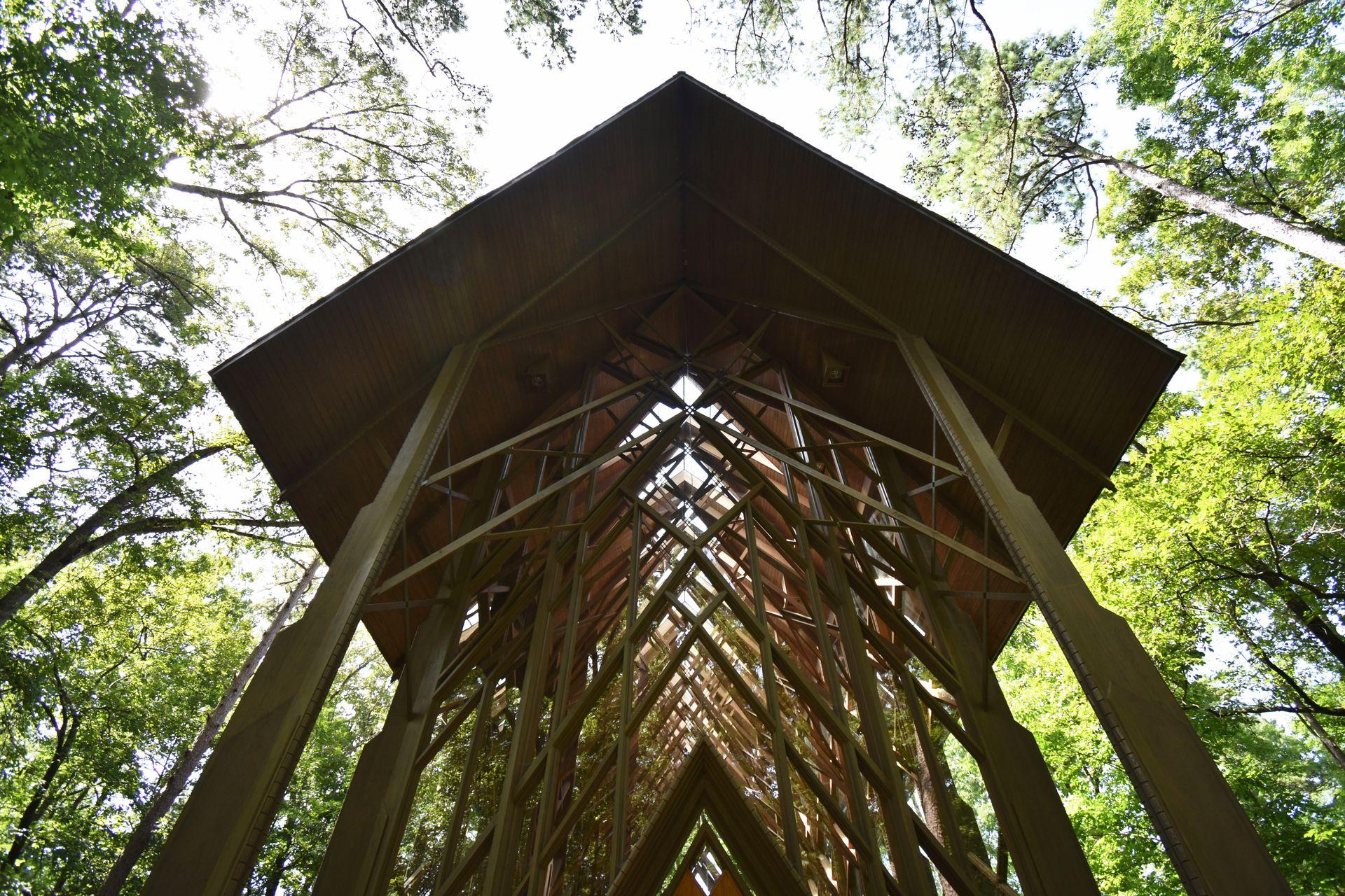 Looking up at the glass chapel at Garven Woodland Gardens. The chapel is surrounded by trees.