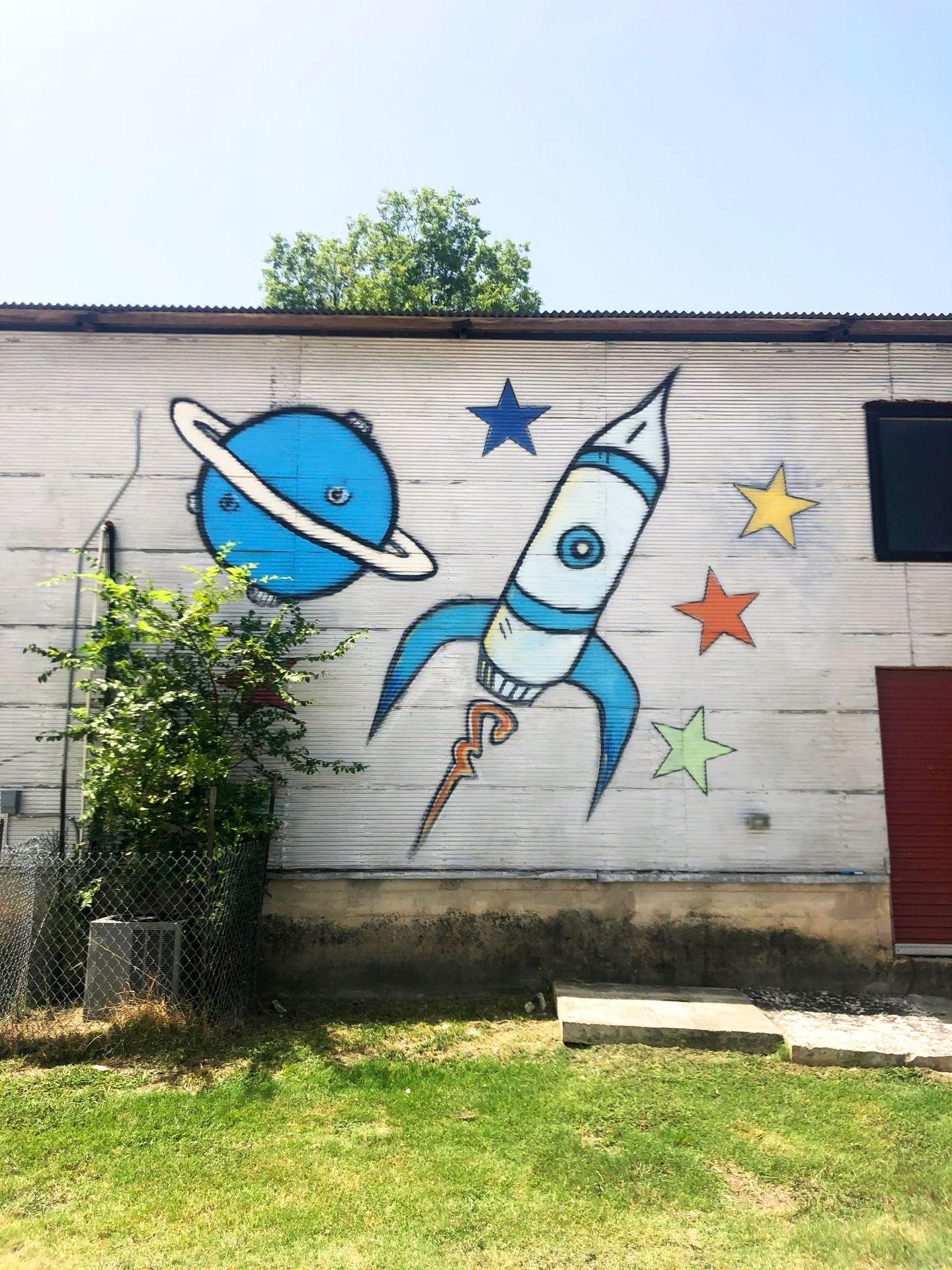 A mural of a rocket ship, a planet and stars.