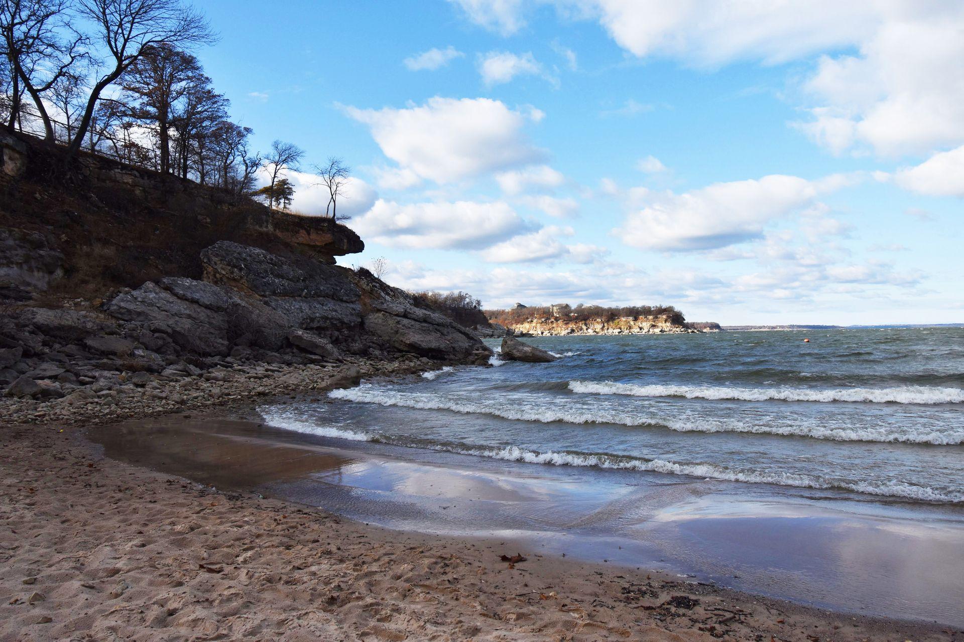 A beach area with a rocky ledge on one side and waves cascading into the shore at Eisenhower State Park.