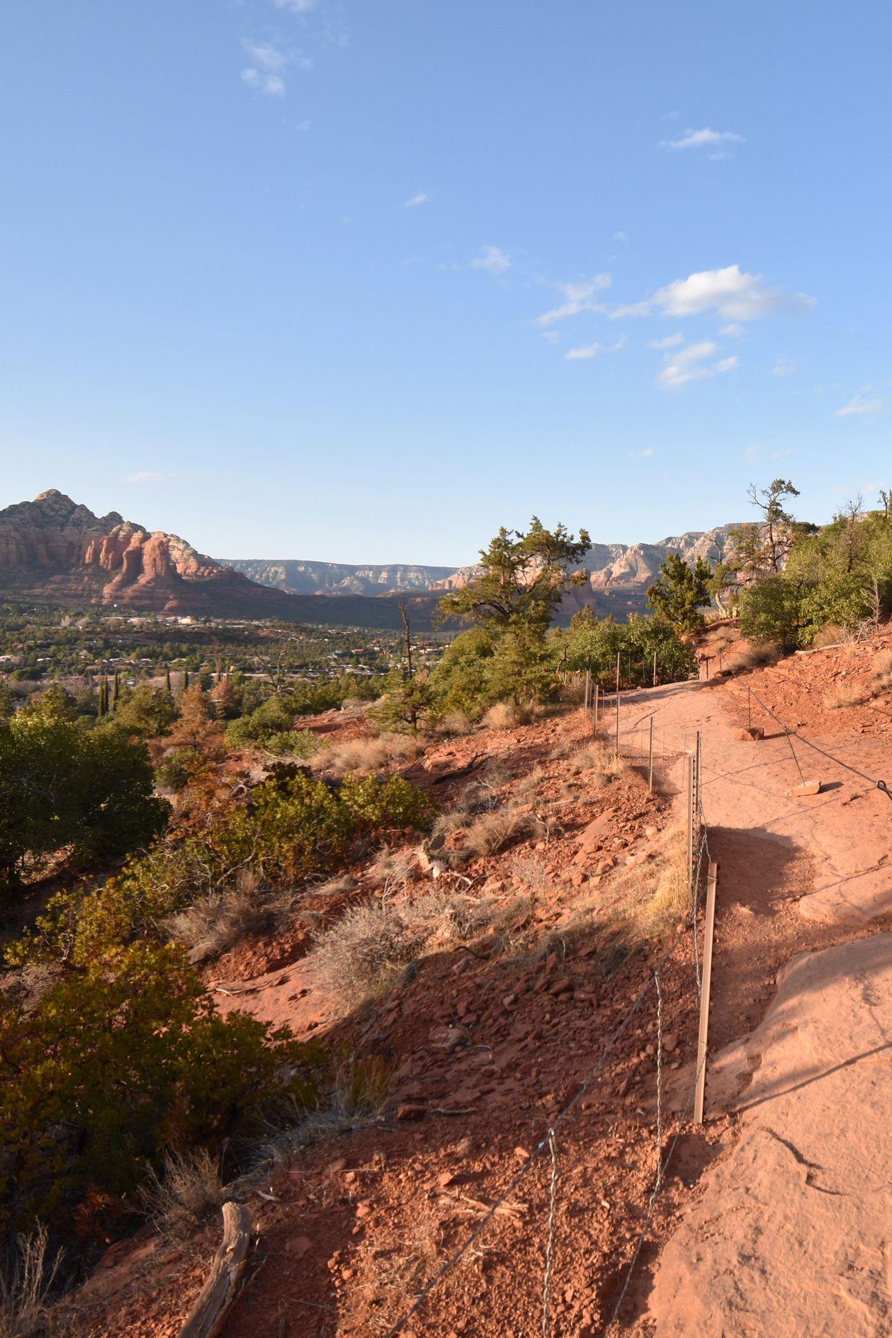 A trail leading to Airport Mesa. There is a railing along the orange rock path.