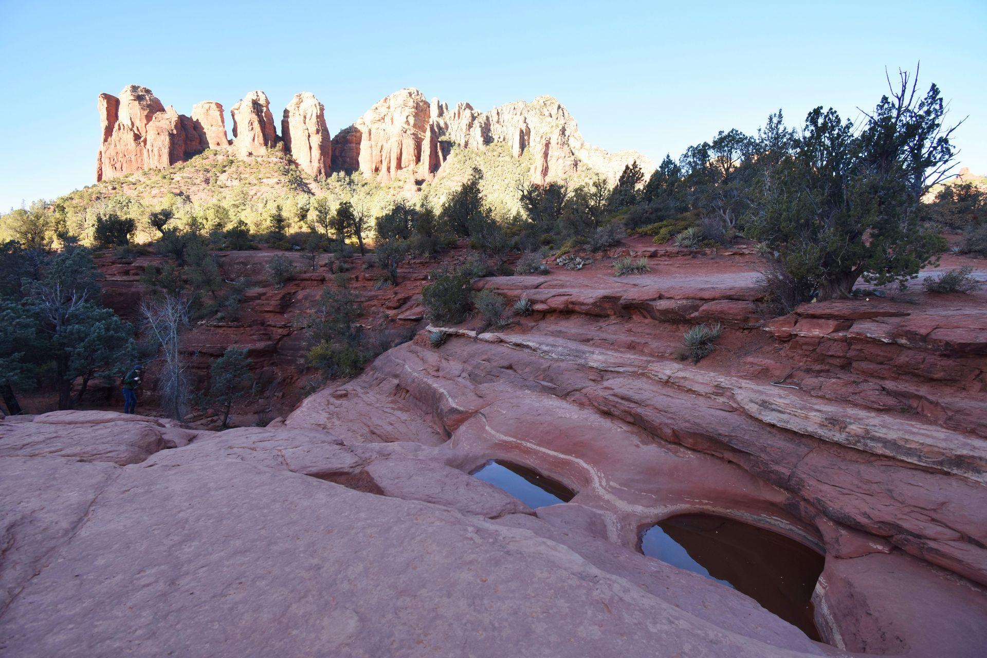 Two pools of water with jagged orange cliffs in the background.