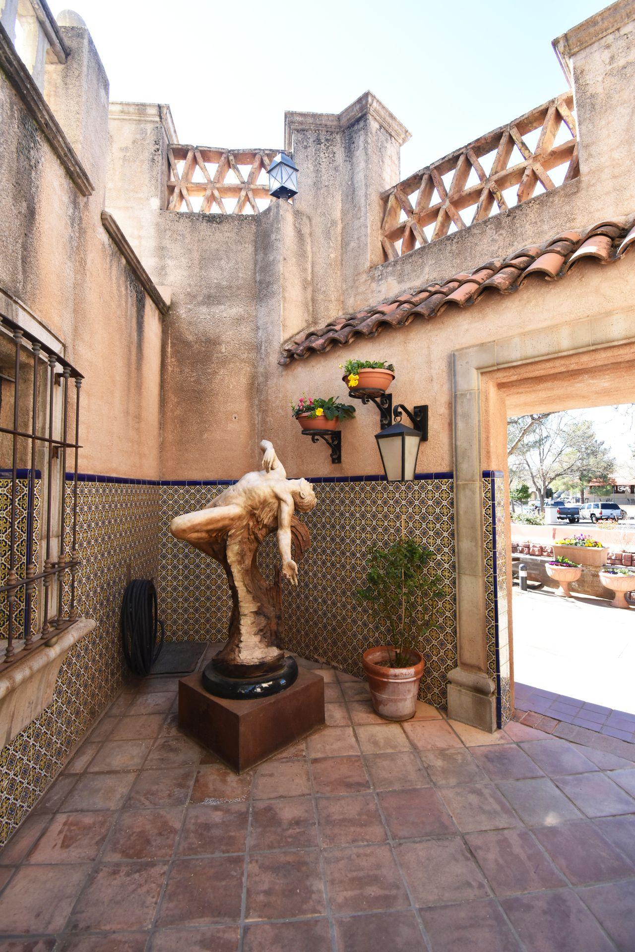 A statue in Tlaquepaque Shopping Village in a corner. The wall behind the statue is half covered in intricately designed tiles.