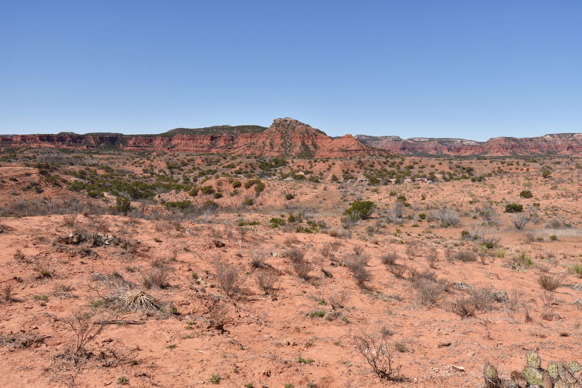 A view of desert and orange rocks in the distance from the Caprock Canyon visitor center