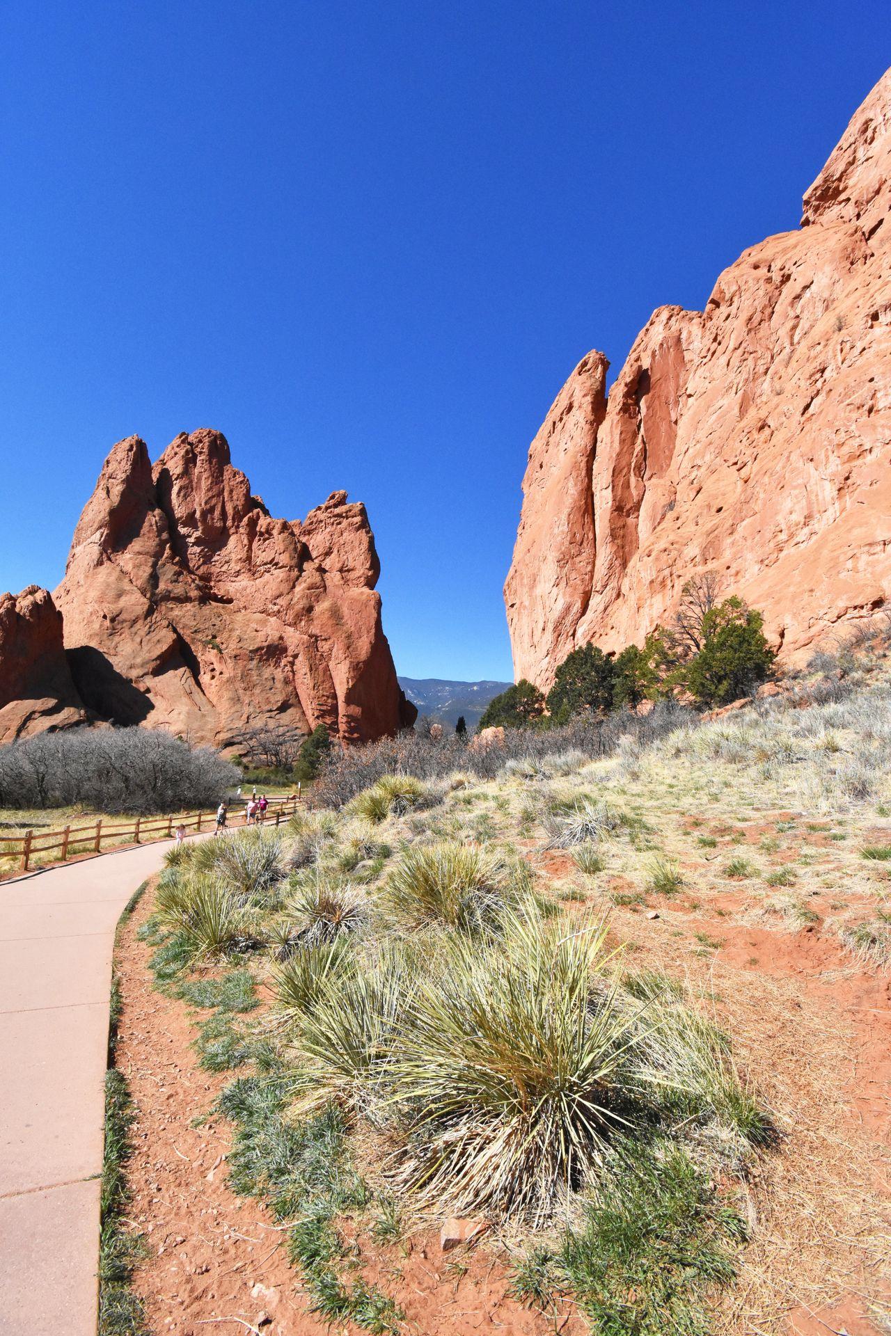 Some large, orange rocks with a paved path going between them.
