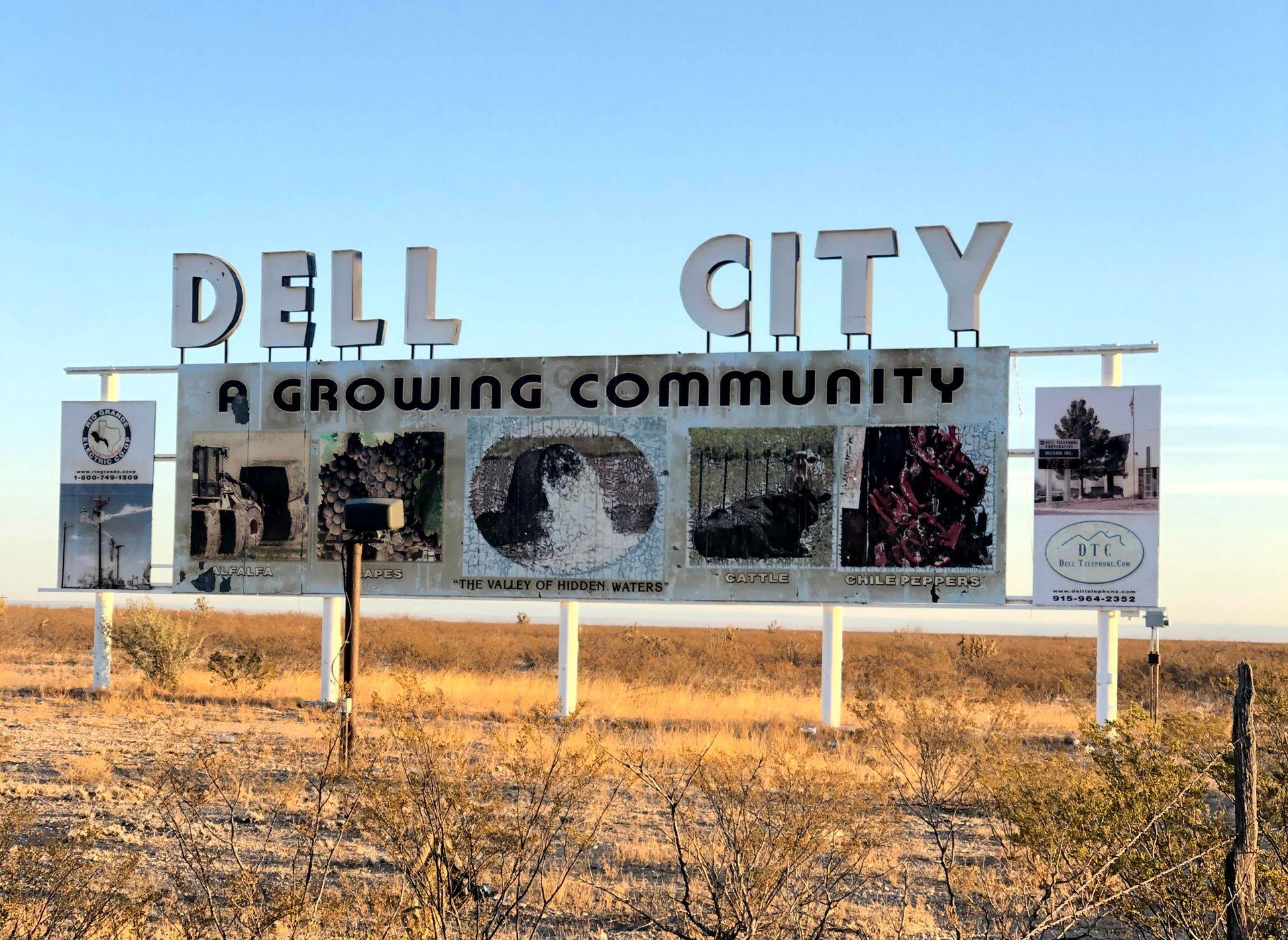 The sign outside of the town of Dell City. It reads "Dell City, A Growing Community" and there are images of chile peppers, cattle and a valley of hidden waters