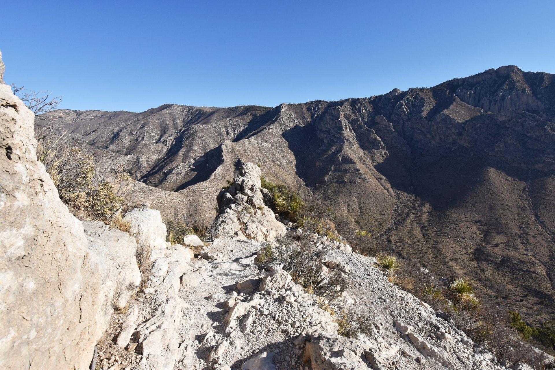 The corner of a switchback on the Guadalupe Peak trail with a mountain view across a valley.