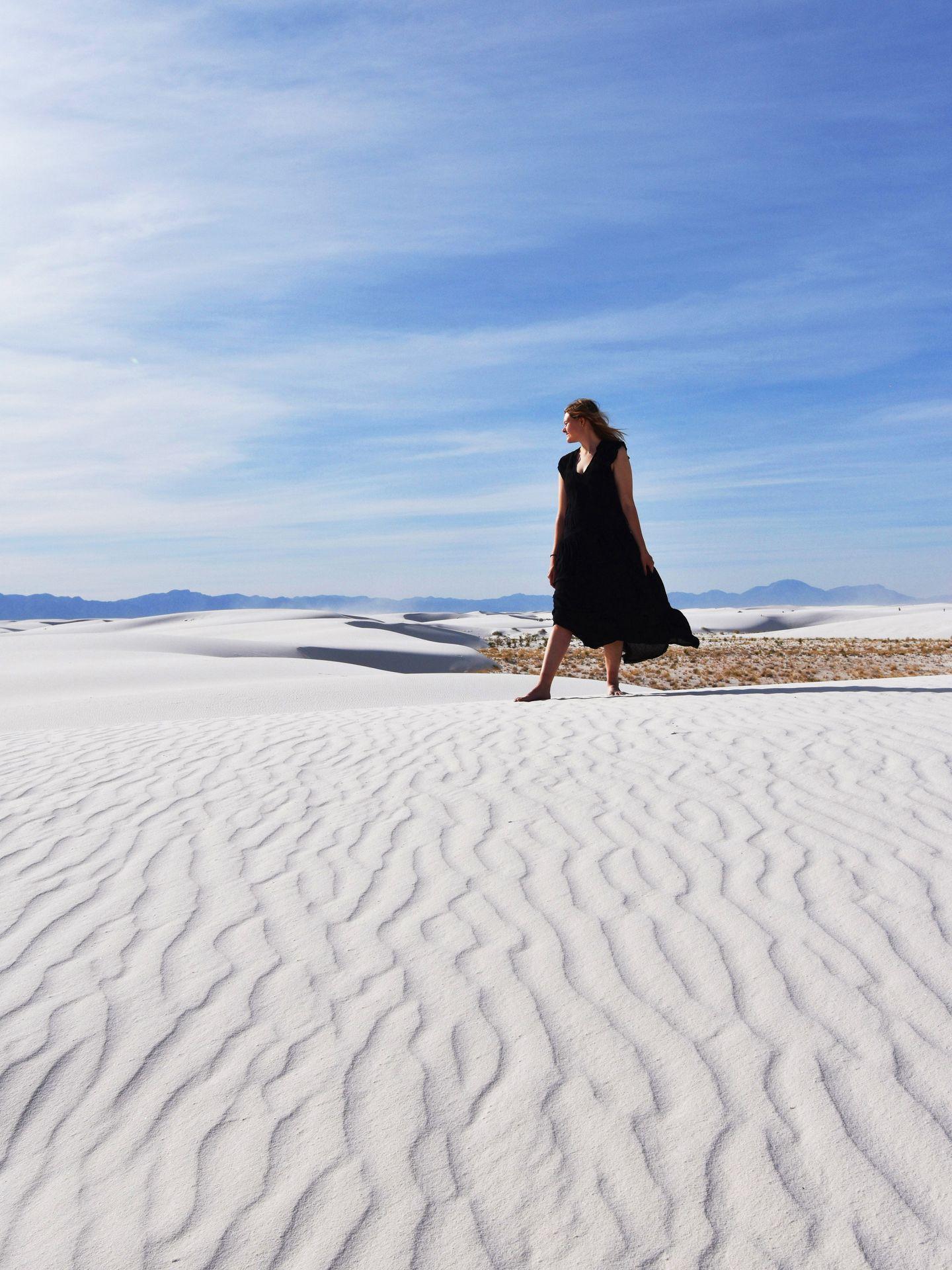 Lydia standing on a sand dune in White Sands wearing a black dress.