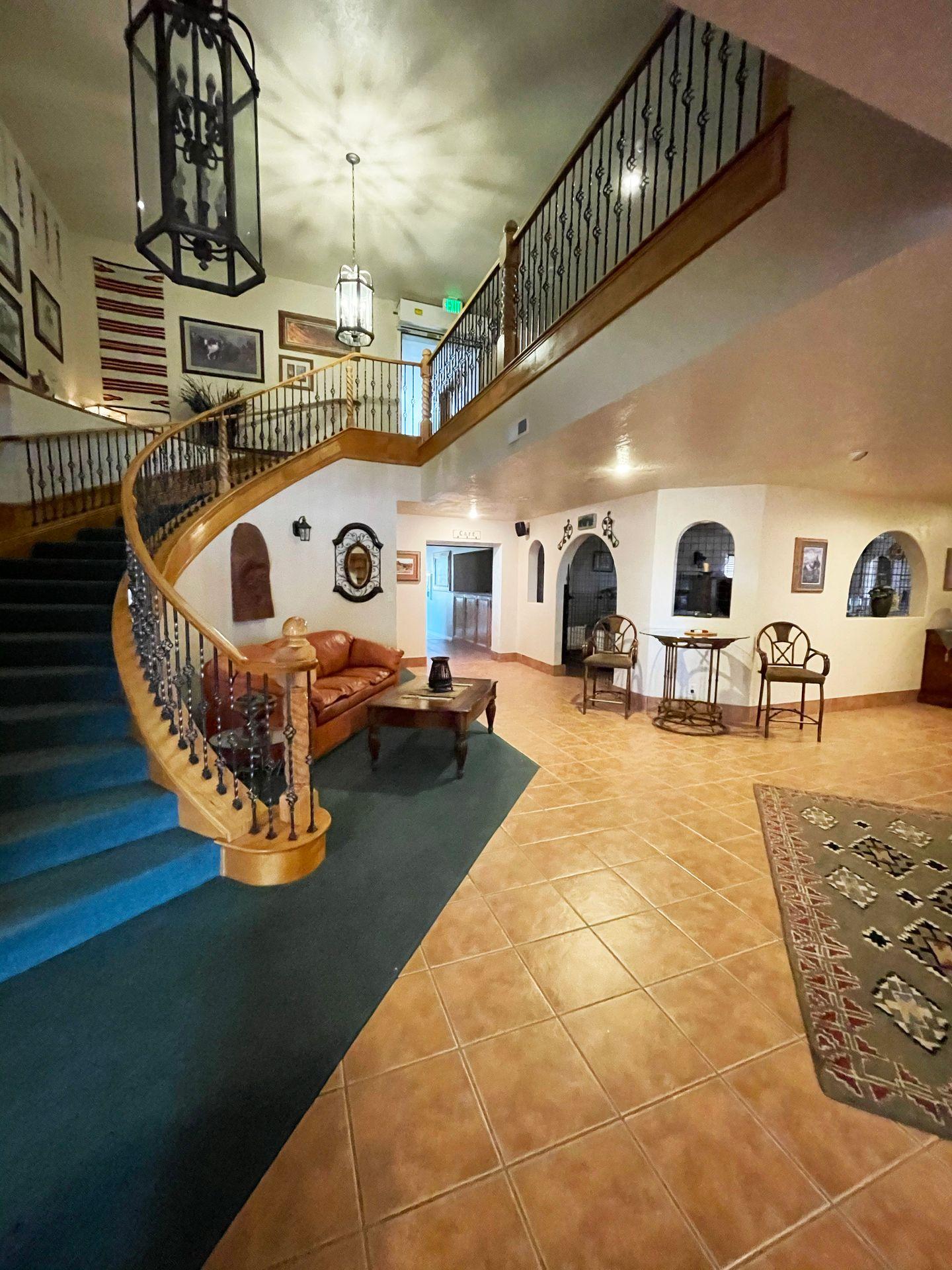 The lobby of the Snuggle Inn. There is a curved staircase, artwork on the walls, a rug and a couch, making the lobby feel welcoming.