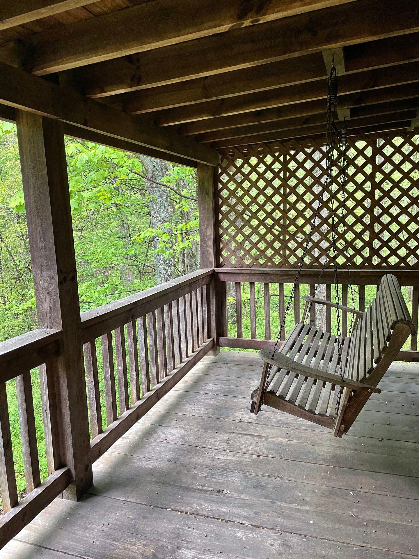 A wooden porch with a swinging bench at a cabin in Hocking Hills.