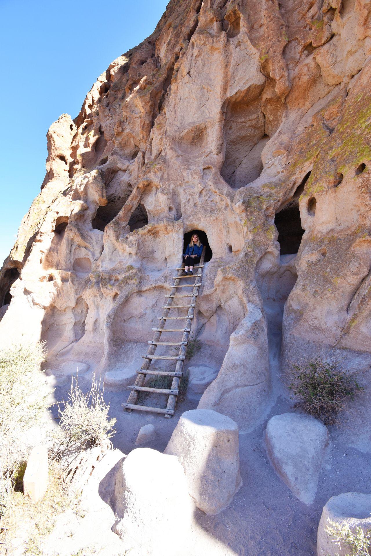 Lydia sitting at the top of a ladder inside a cave dwelling at Bandelier National Monument.