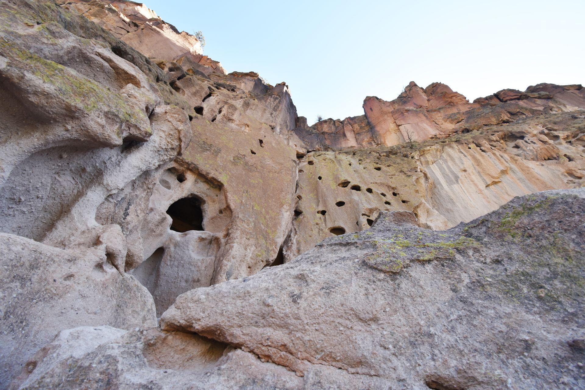 Looking up at a rock face with some interesting holes in it at Bandelier National Monument.