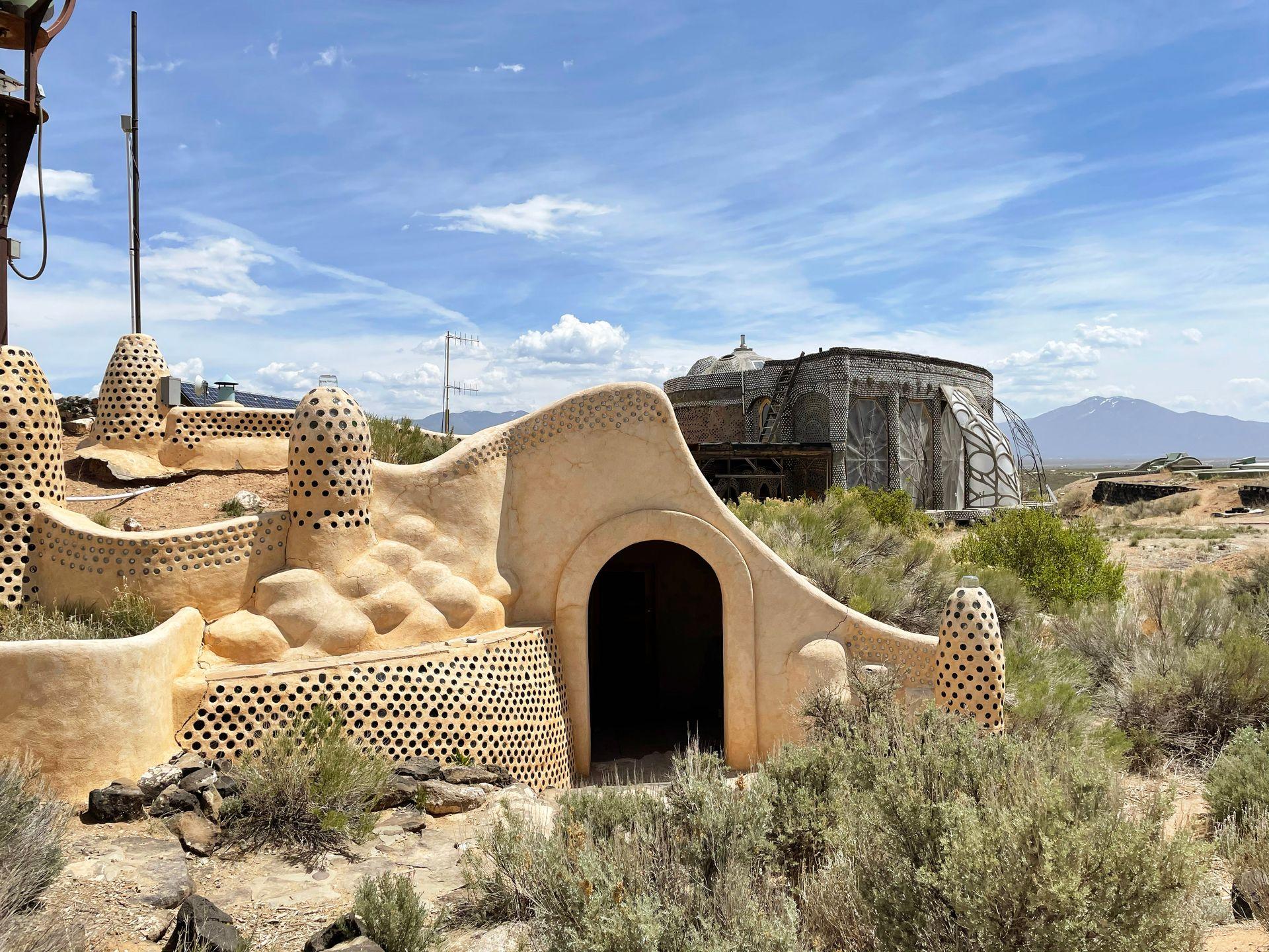 The exterior of the Earthship Biotecture Visitor Center. The building is shaped organically and made with natural and recycled material.